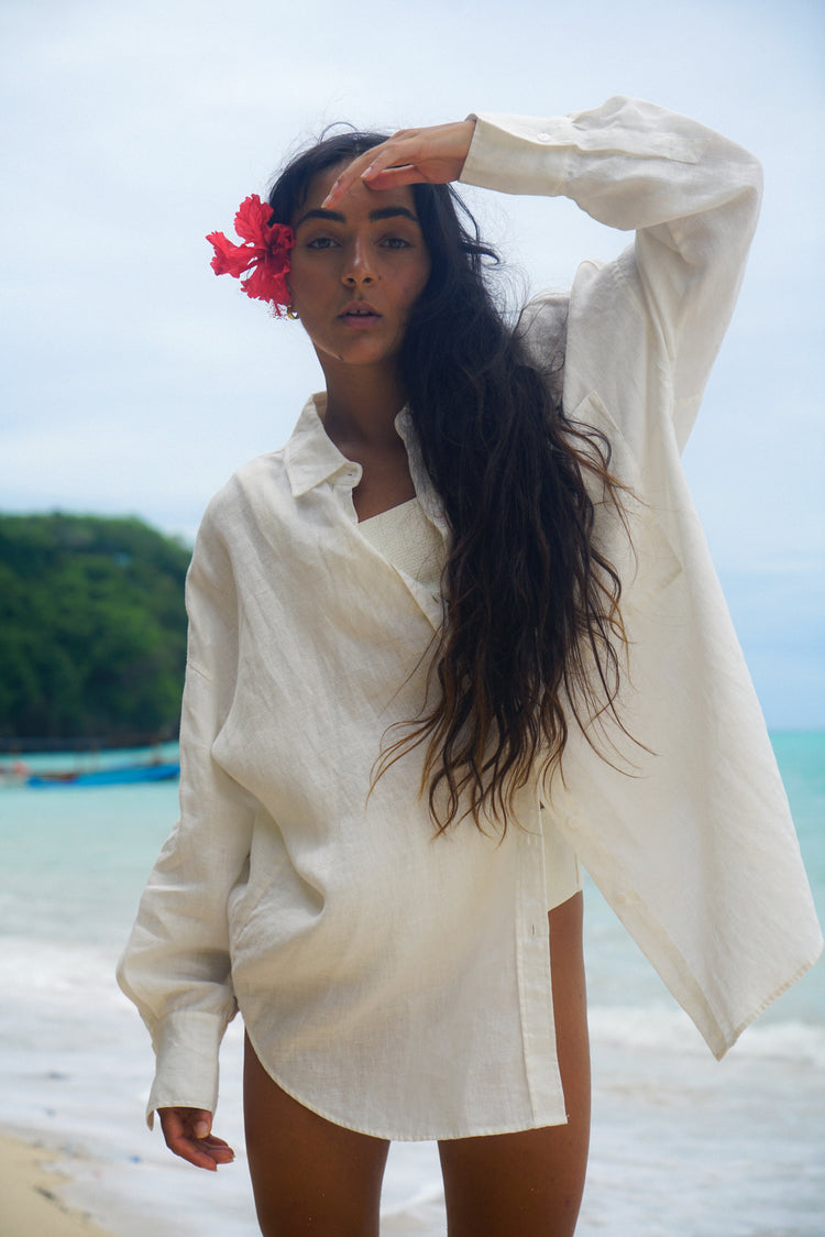 Kirra Linen Shirt in Ivory - front view, worn oversized and unbuttoned over swimwear, tropical beach backdrop - Lilly Pilly Collection