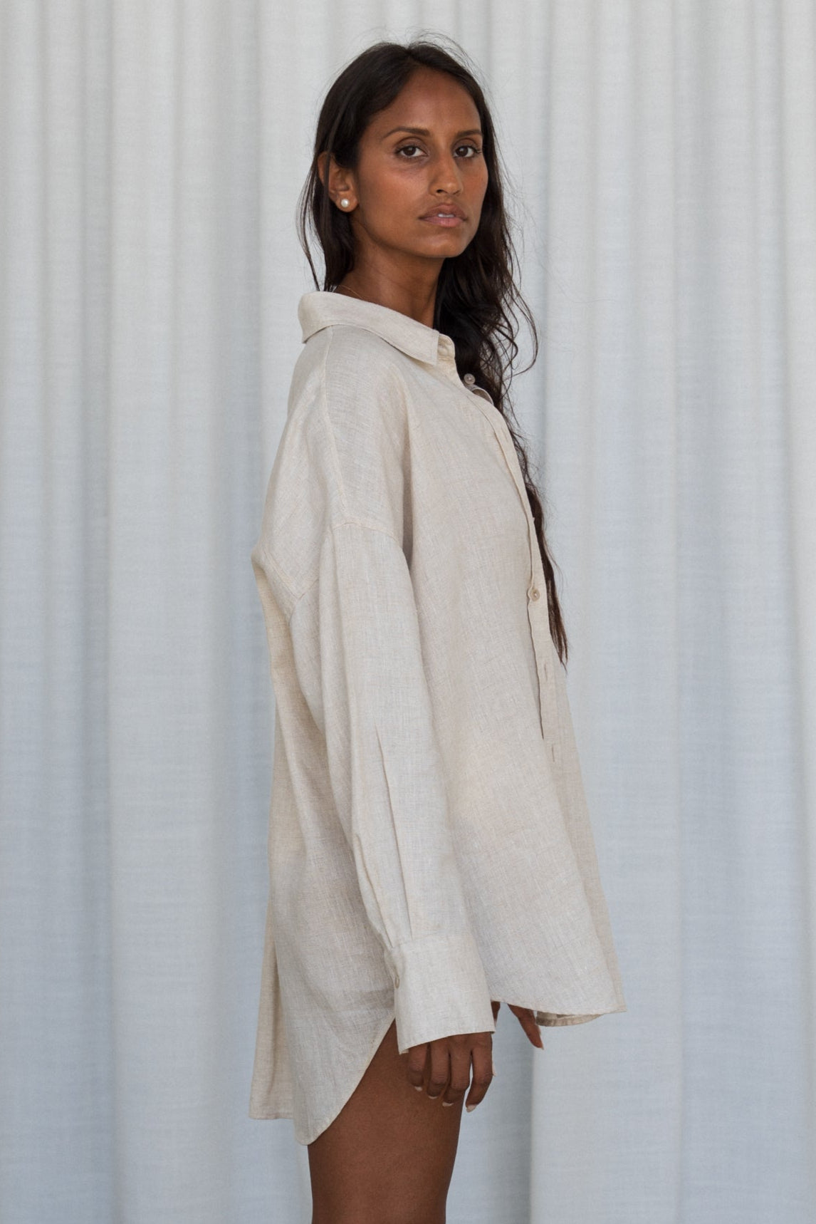 LILLY PILLY woman wearing a oatmeal Kirra linen shirt top against a white curtain background
