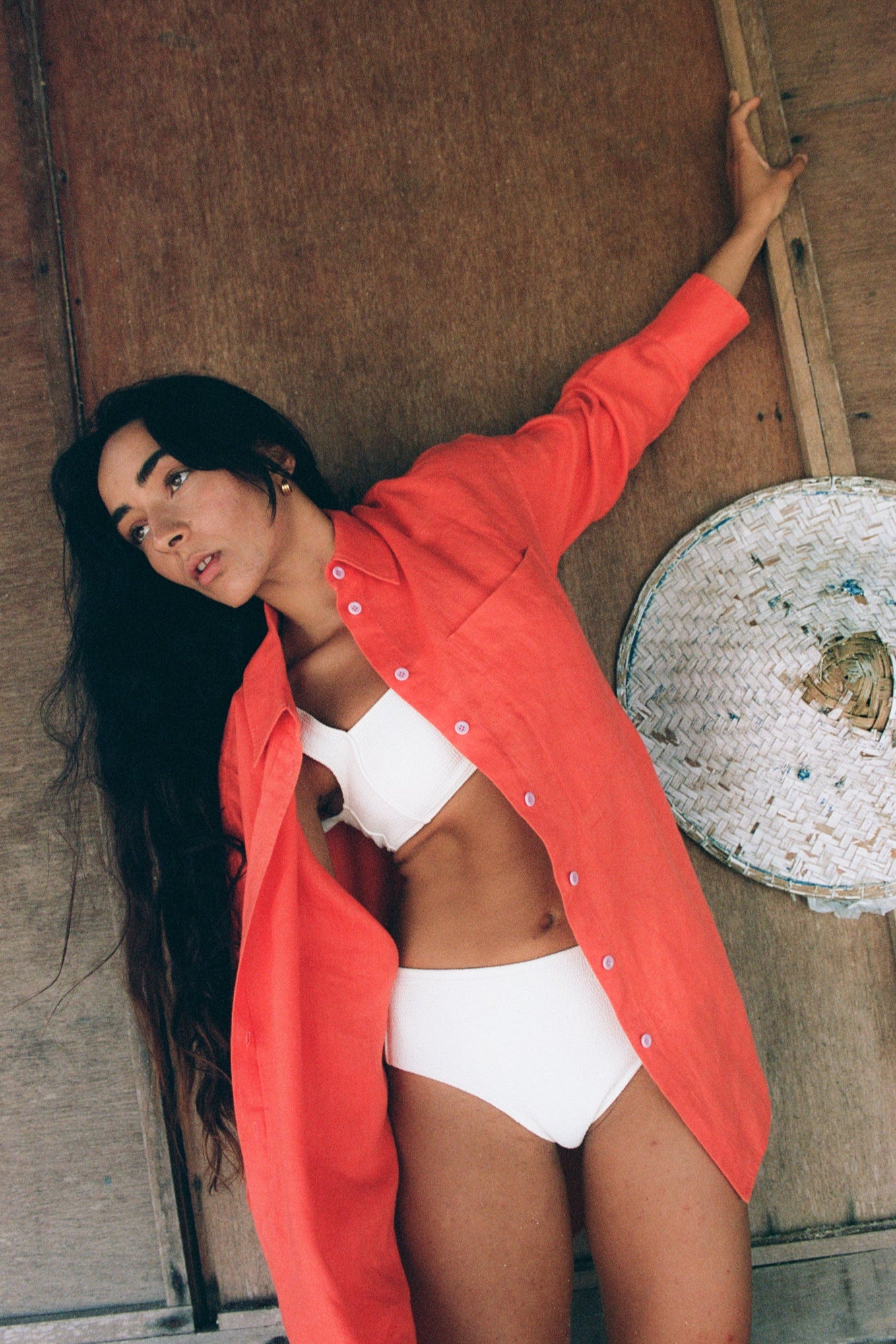 LILLY PILLY woman wearing a spritz Kirra linen shirt standing against a textured wall.