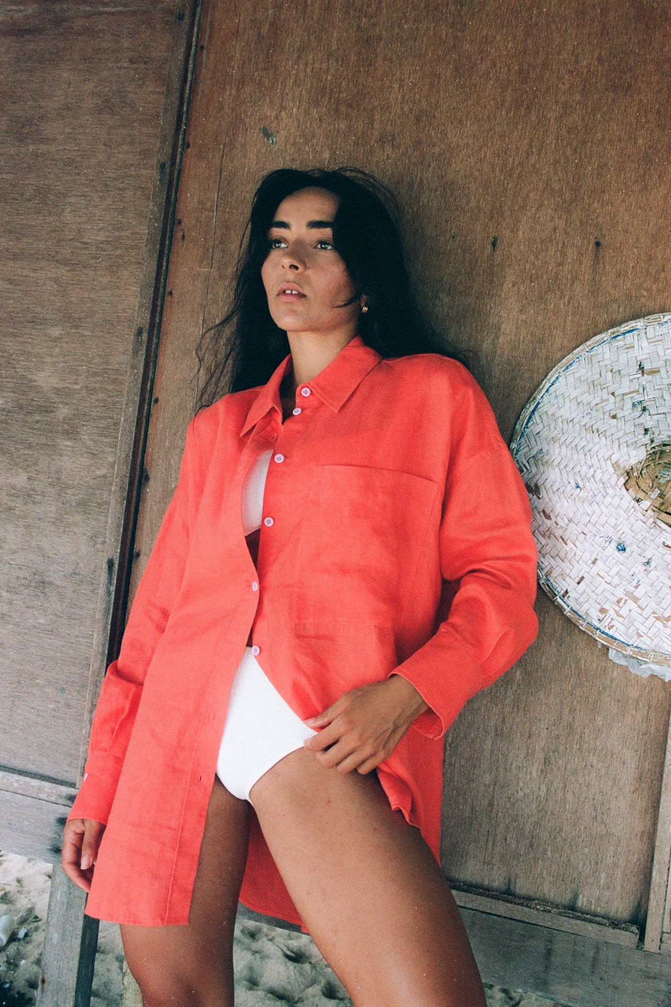 LILLY PILLY woman wearing a spritz Kirra linen shirt leaning against a  wooden wall.