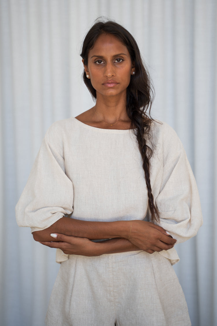 Leia Linen Top in Oatmeal - front view, arms crossed, boat neckline and puff sleeves, worn with matching shorts, studio setting - Lilly Pilly Collection