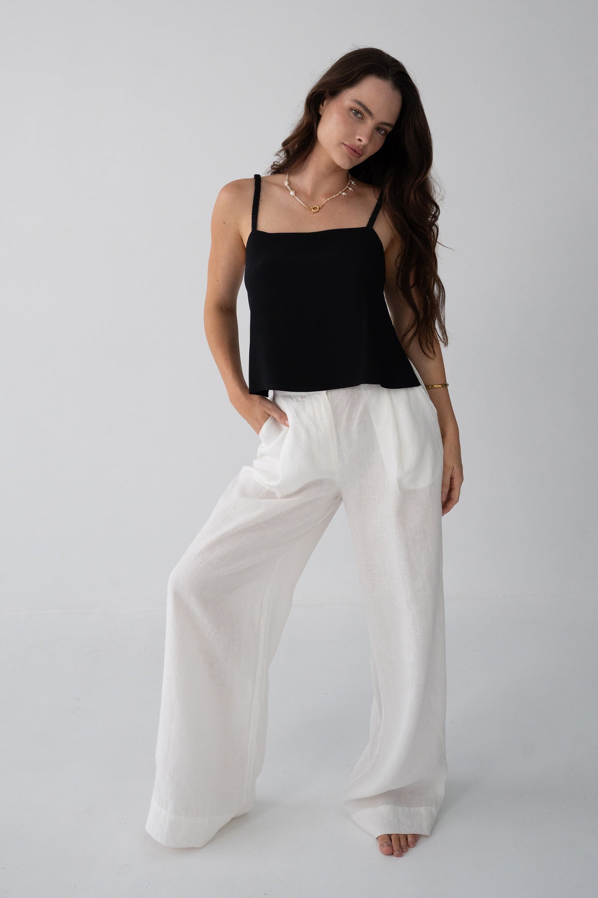 Leni Silk Cami in Black - front view, square neckline and thin straps, worn with ivory wide-leg Oli linen pants, hand in pocket - Lilly Pilly Collection