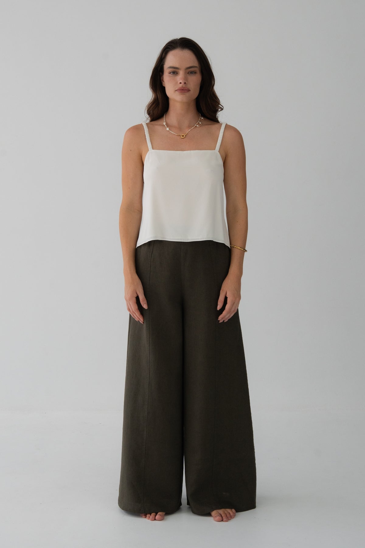 Letty Linen Pants in Khaki - full length front view, woman wearing Khaki wide-leg linen pants with ivory silk cami, studio backdrop - Lilly Pilly Collection