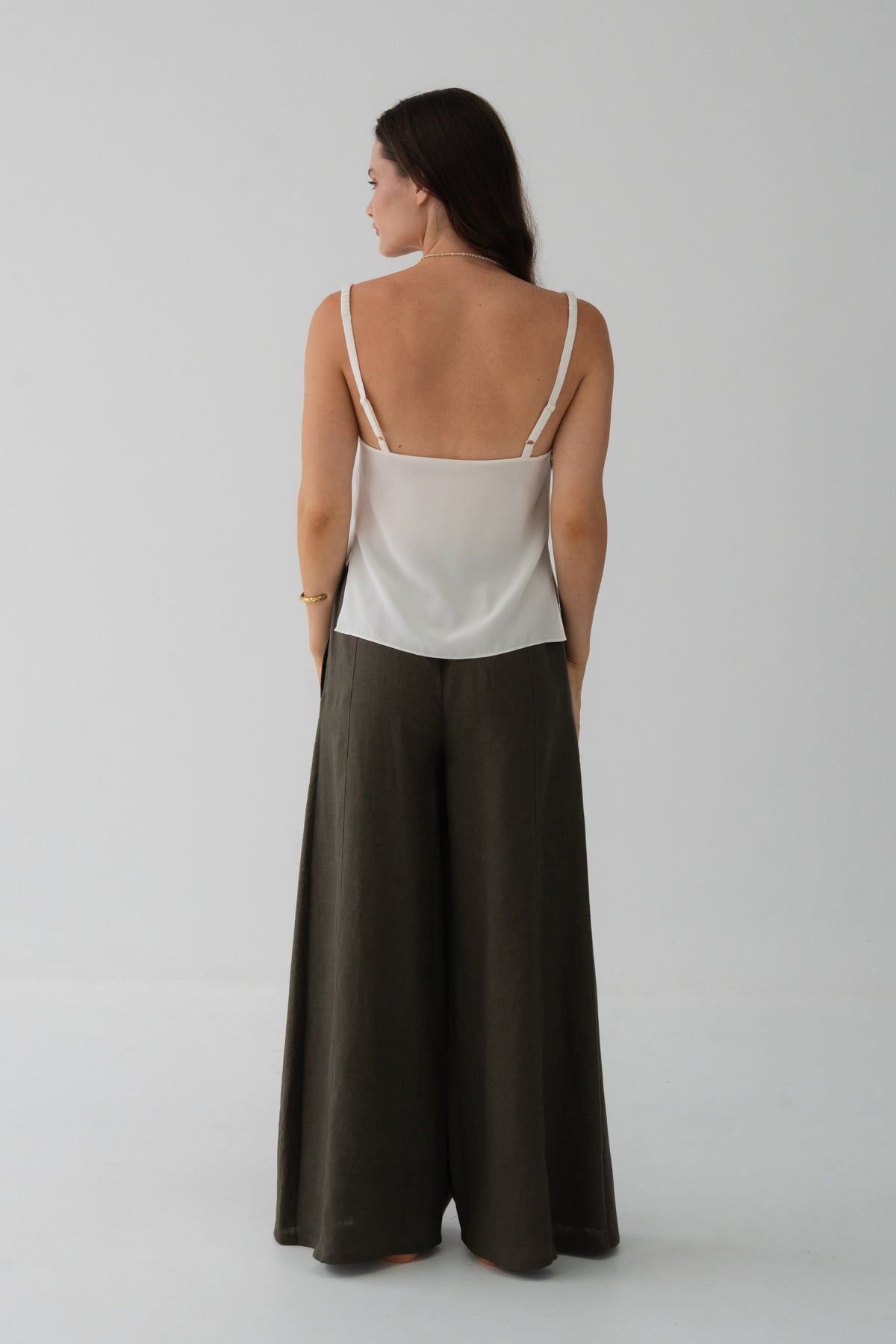 Letty Linen Pants in Khaki - back view, woman wearing Khaki wide-leg linen pants with ivory silk cami, studio backdrop - Lilly Pilly Collection