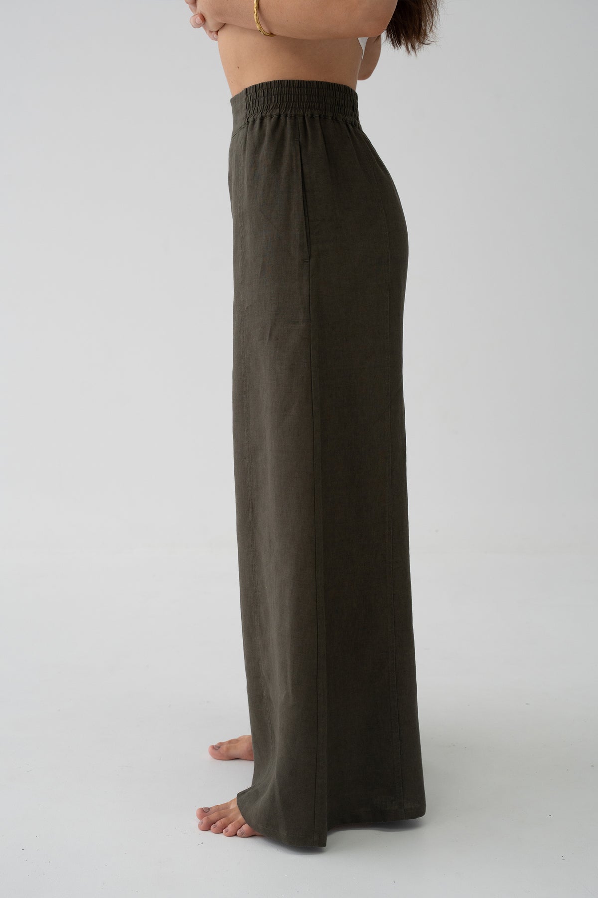 Letty Linen Pants in Khaki - side view close-up of elasticated waistband and wide-leg linen drape, studio setting - Lilly Pilly Collection