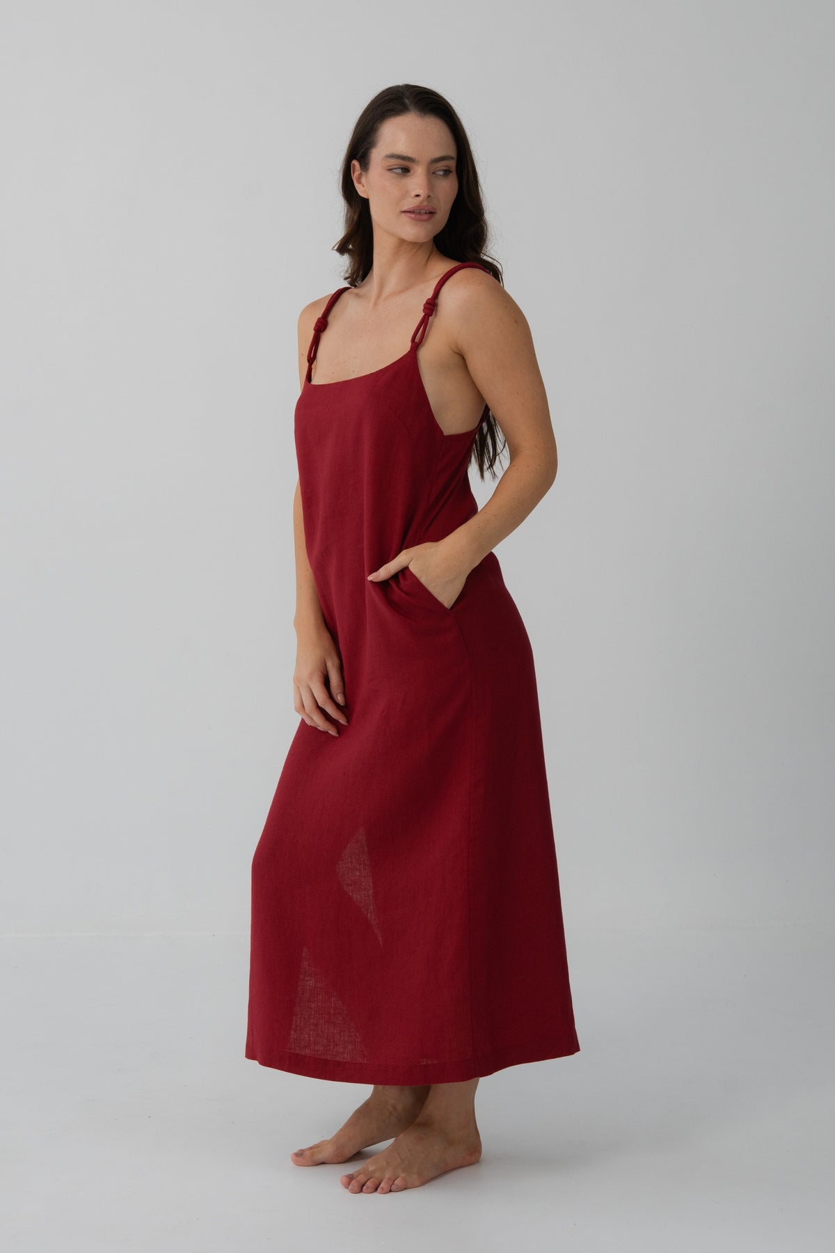Lia Linen Midi Slip Dress in Cherry Red - three-quarter view, hand in pocket, relaxed midi silhouette - Lilly Pilly Collection