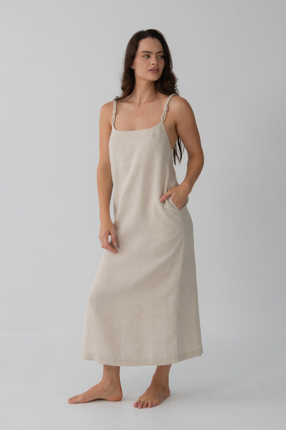 Lia Linen Midi Slip Dress in Oatmeal - three-quarter front view, hand in pocket, relaxed silhouette - Lilly Pilly Collection