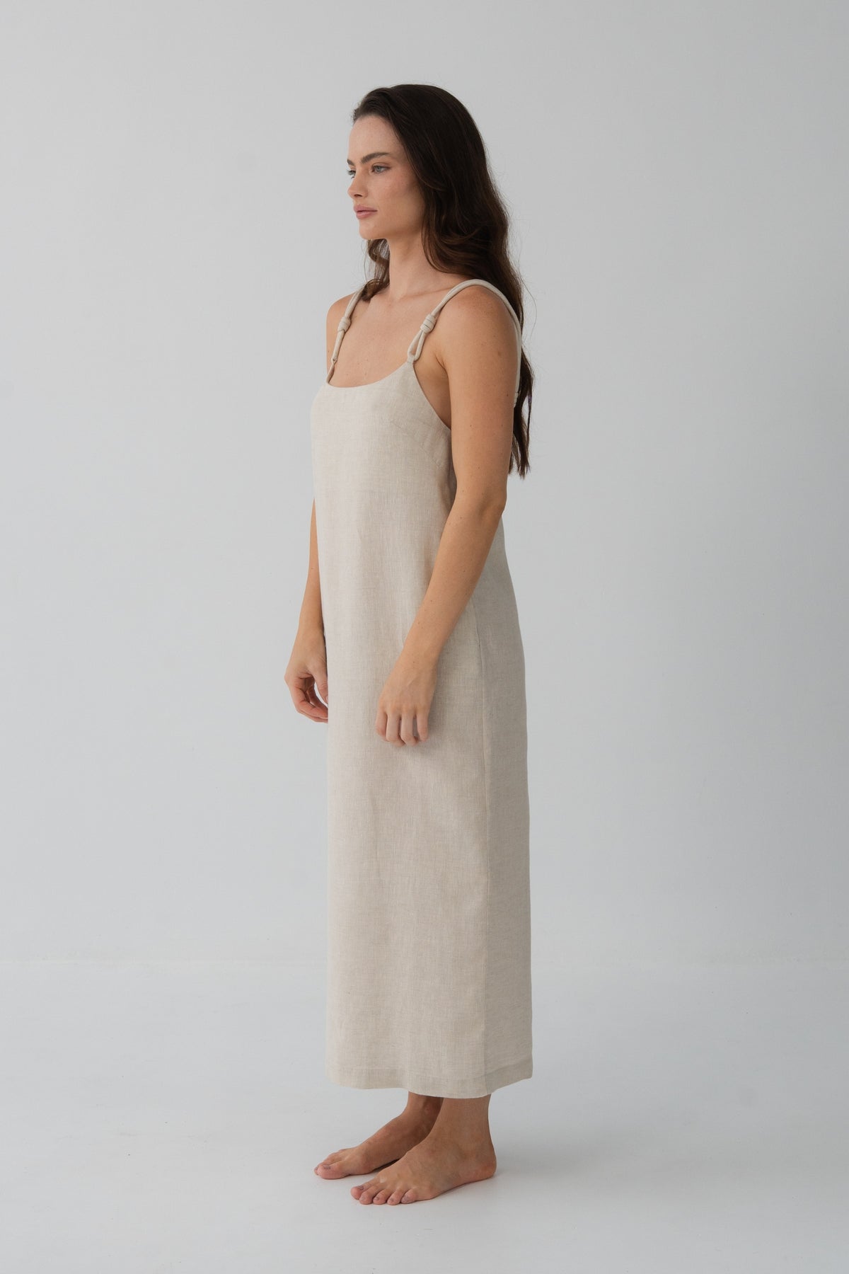 Lia Linen Midi Slip Dress in Oatmeal - three-quarter front view, hand in pocket, relaxed silhouette - Lilly Pilly Collection