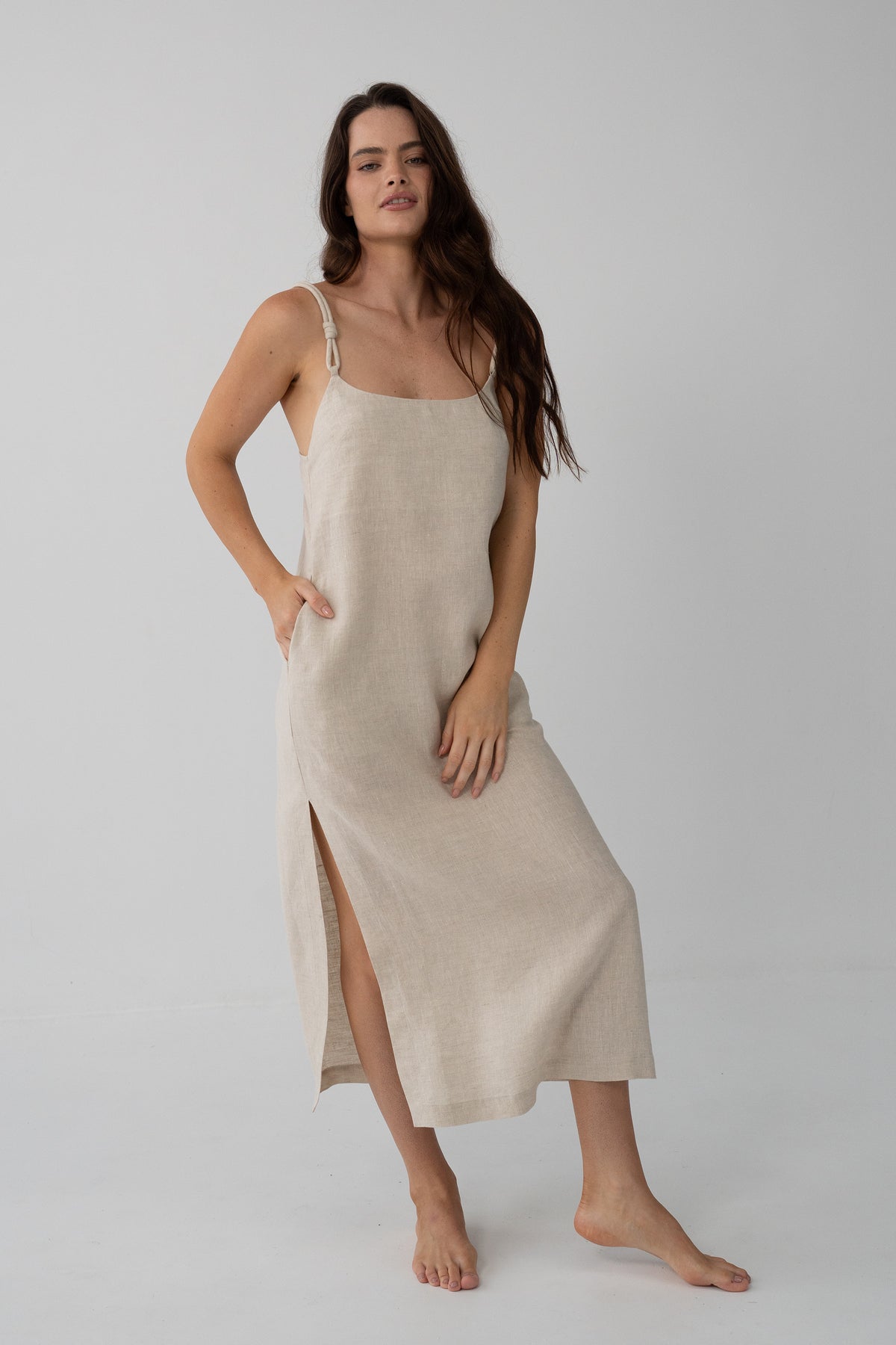 Lia Linen Midi Slip Dress in Oatmeal - full front view, scoop neckline and braided straps, hand in pocket - Lilly Pilly Collection