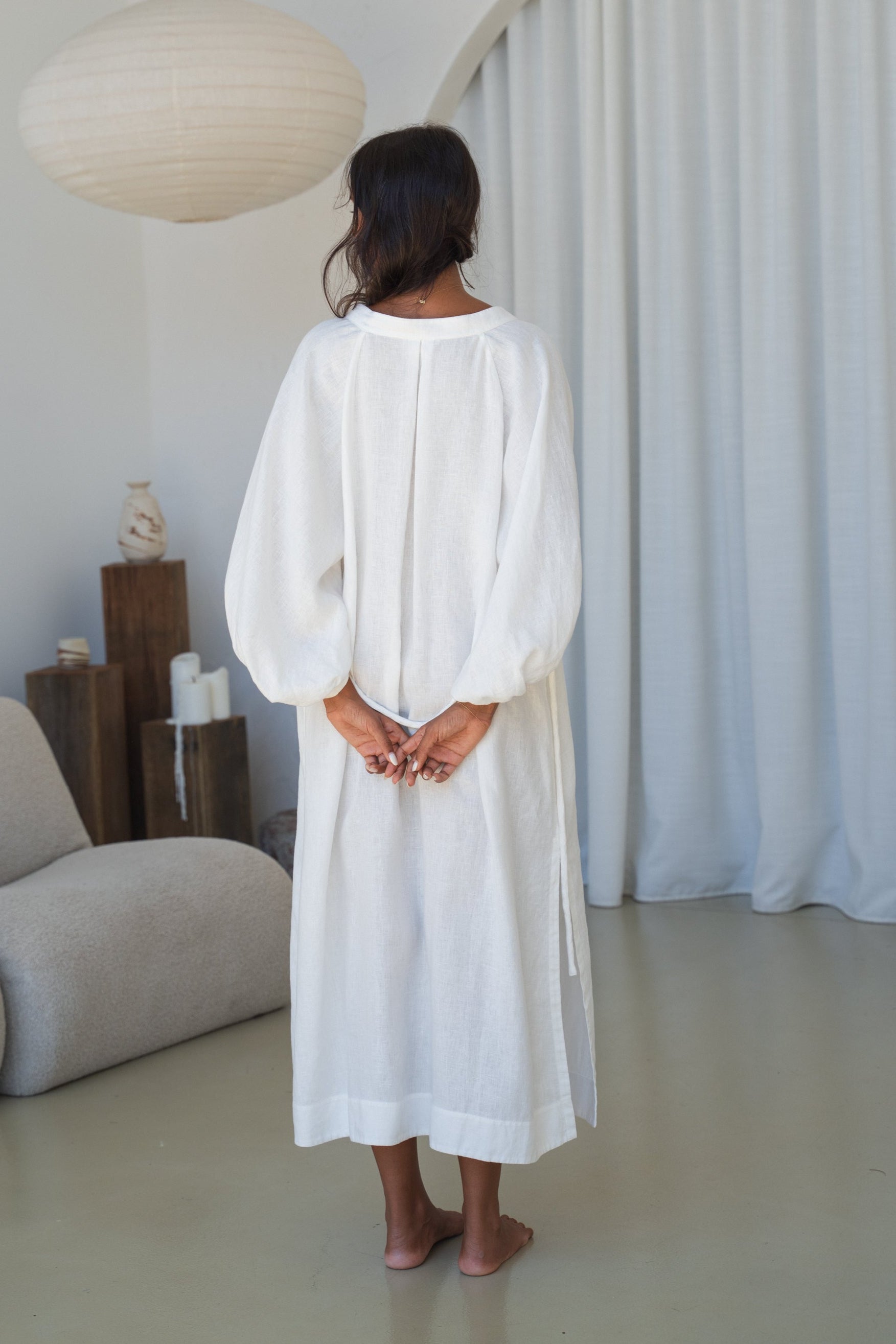 Woman in an ivory Mae linen dress in studio back view