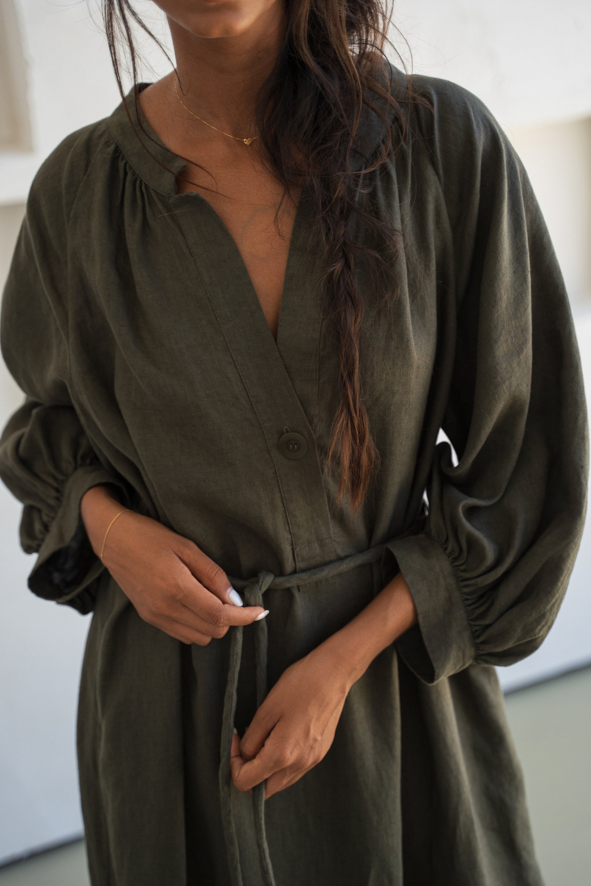 Woman wearing a khaki Mae linen dress in studio, front view close up