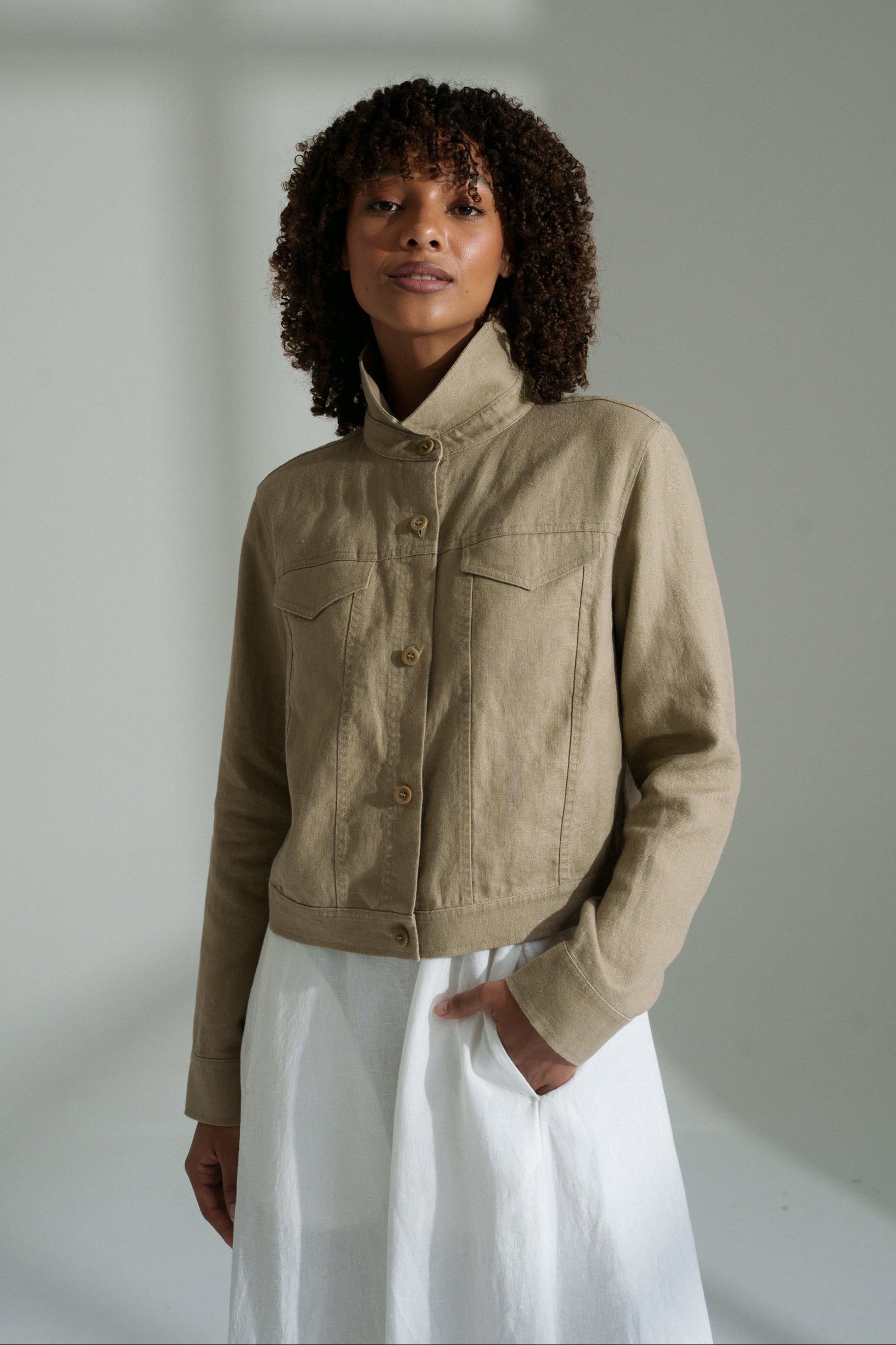 LILLY PILLY woman wearing a taupe Milly linen jacket and white pants against a plain background