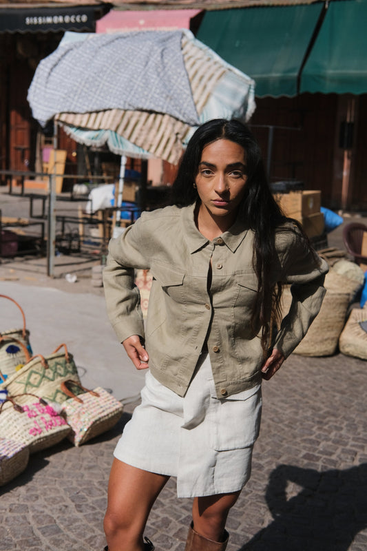 LILLY PILLY woman wearing a taupe Milly linen jacket standing outdoors with a market scene in the background