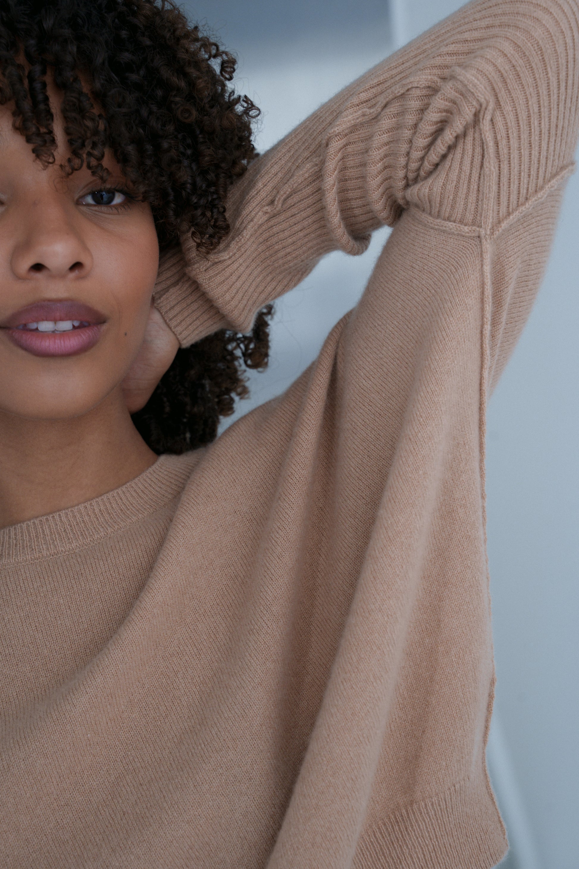 Close up of LILLY PILLY woman wearing Camel brown Miri cashmere knit sweater with arm raised