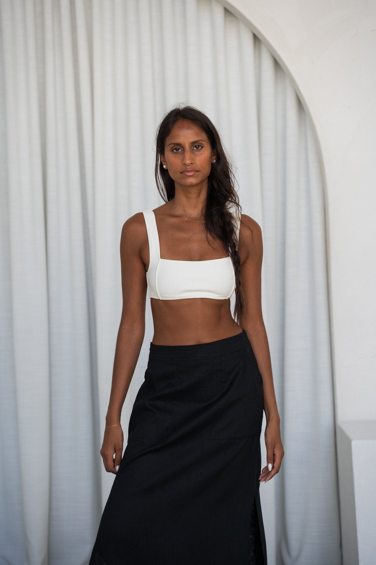 woman wearing black Nadi linen skirt standing against a white curtain background
