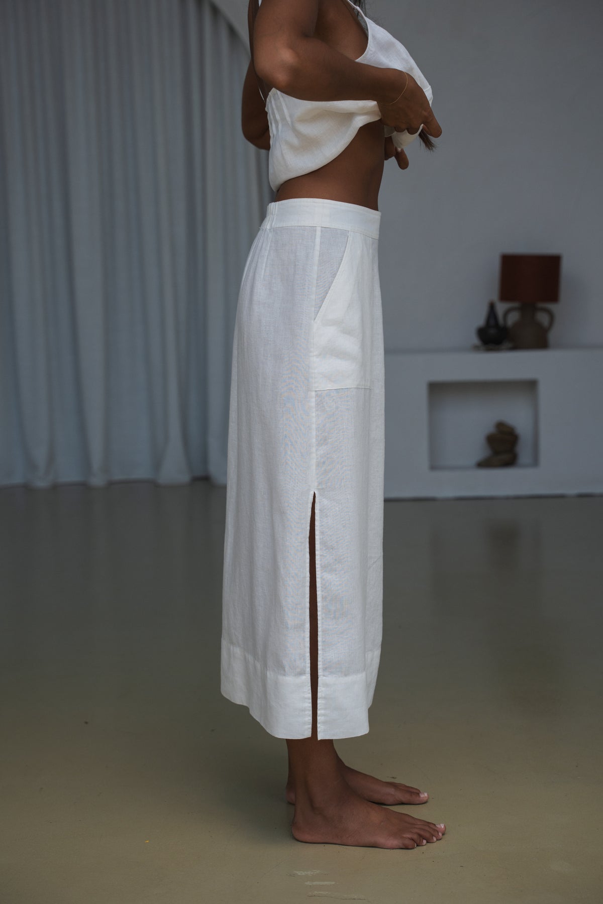 LILLY PILLY woman in an ivory white Nadi skirt close up side view in a minimal indoor setting