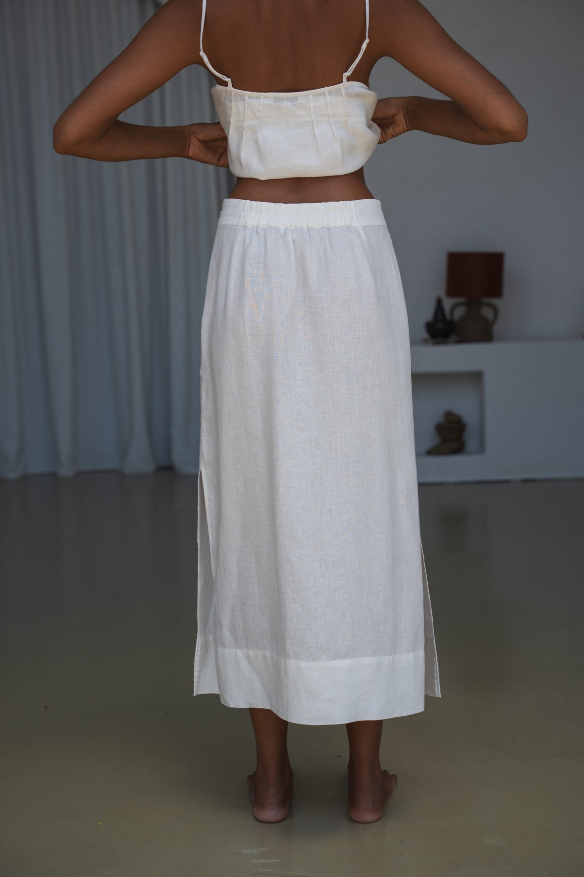 LILLY PILLY woman in an ivory white Nadi skirt back view in a minimal indoor setting