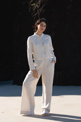 Oli Linen Pants in Oatmeal - full length front view, woman wearing Oatmeal wide-leg linen pants with matching Milly linen jacket, sandy beach with dark cliff backdrop - Lilly Pilly Collection