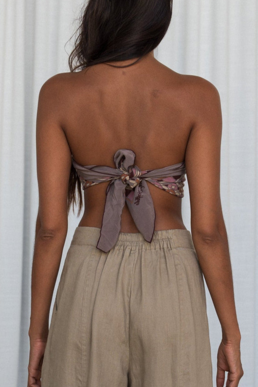 LILLY PILLY woman wearing Oli linen pants in Taupe close up back view with white curtain background