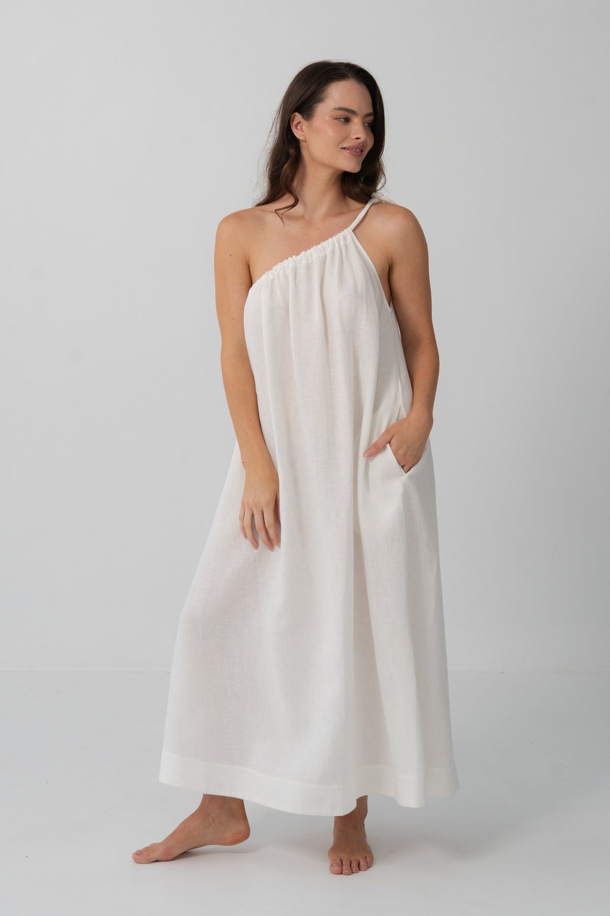 Ophelia Linen Midi Dress in Ivory - full length view, asymmetric gathered neckline, hand in pocket - Lilly Pilly Collection