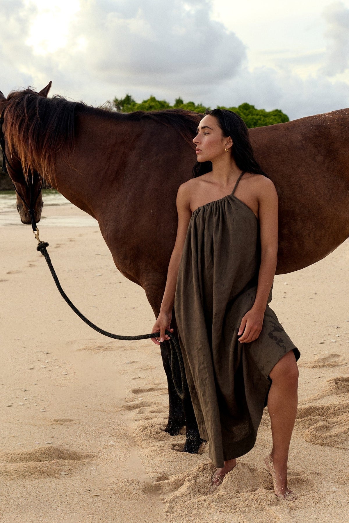 Ophelia Linen Midi Dress in Khaki - woman with horse on beach, asymmetric gathered neckline and voluminous midi silhouette - Lilly Pilly Collection