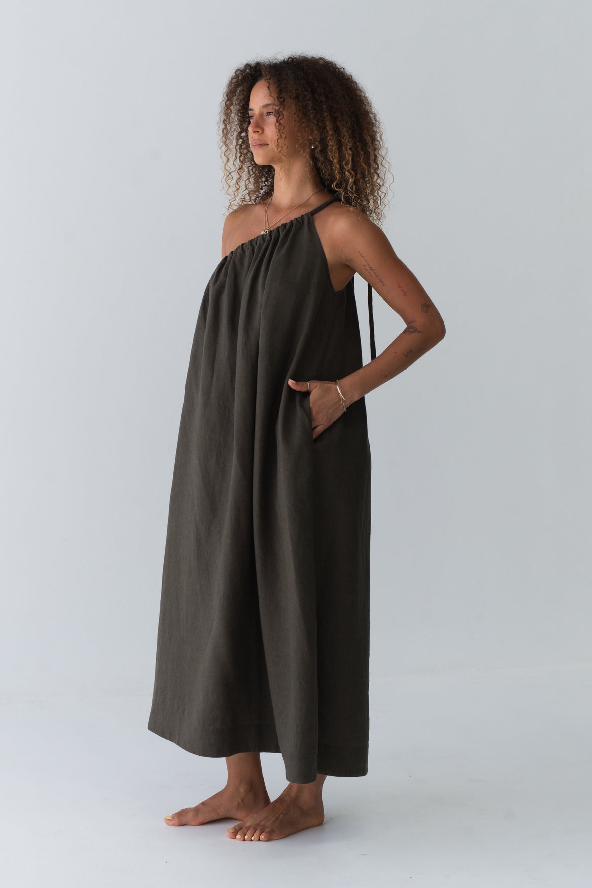 Ophelia Linen Midi Dress in Khaki - side profile, hand in pocket, voluminous A-line midi silhouette - Lilly Pilly Collection