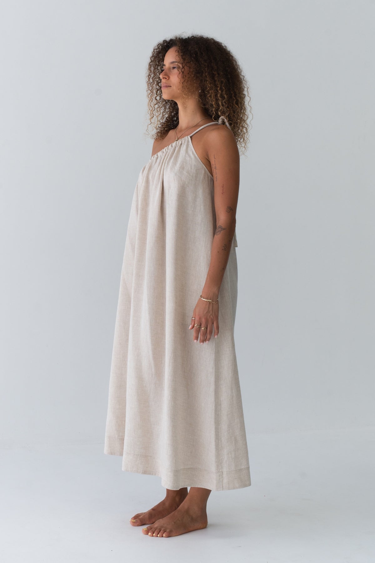 Ophelia Linen Midi Dress in Oatmeal - side profile, asymmetric gathered neckline and fluid midi silhouette - Lilly Pilly Collection