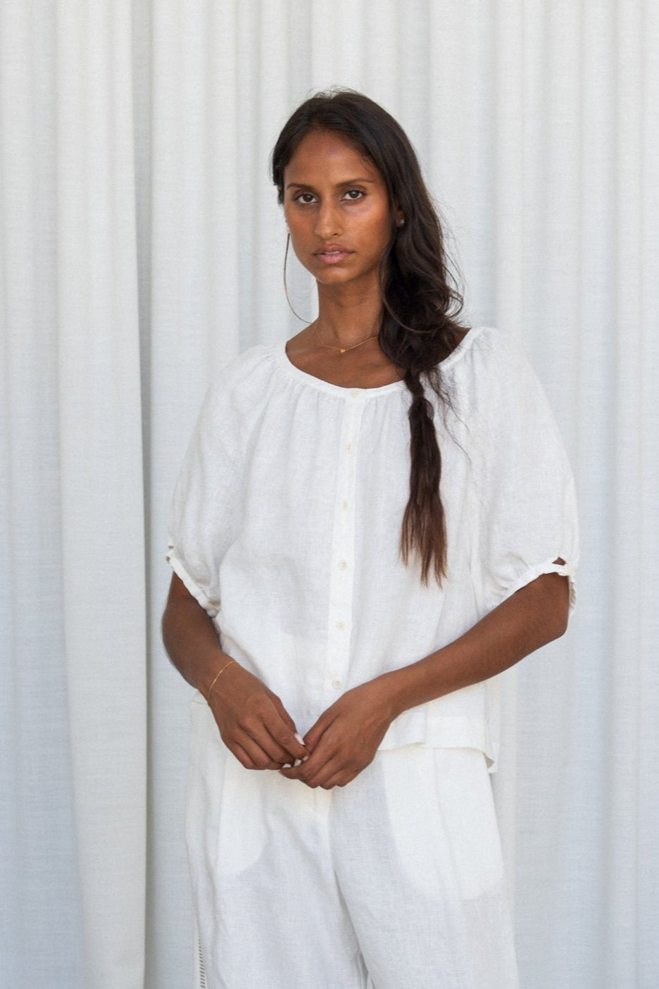 LILLY PILLY woman wearing an ivory Pia linen shirt top and pants outfit against a plain background