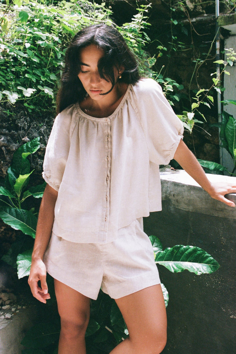 Pia Linen Top in Oatmeal - front view, gathered neckline and button-front, styled with matching linen shorts, garden setting - Lilly Pilly Collection