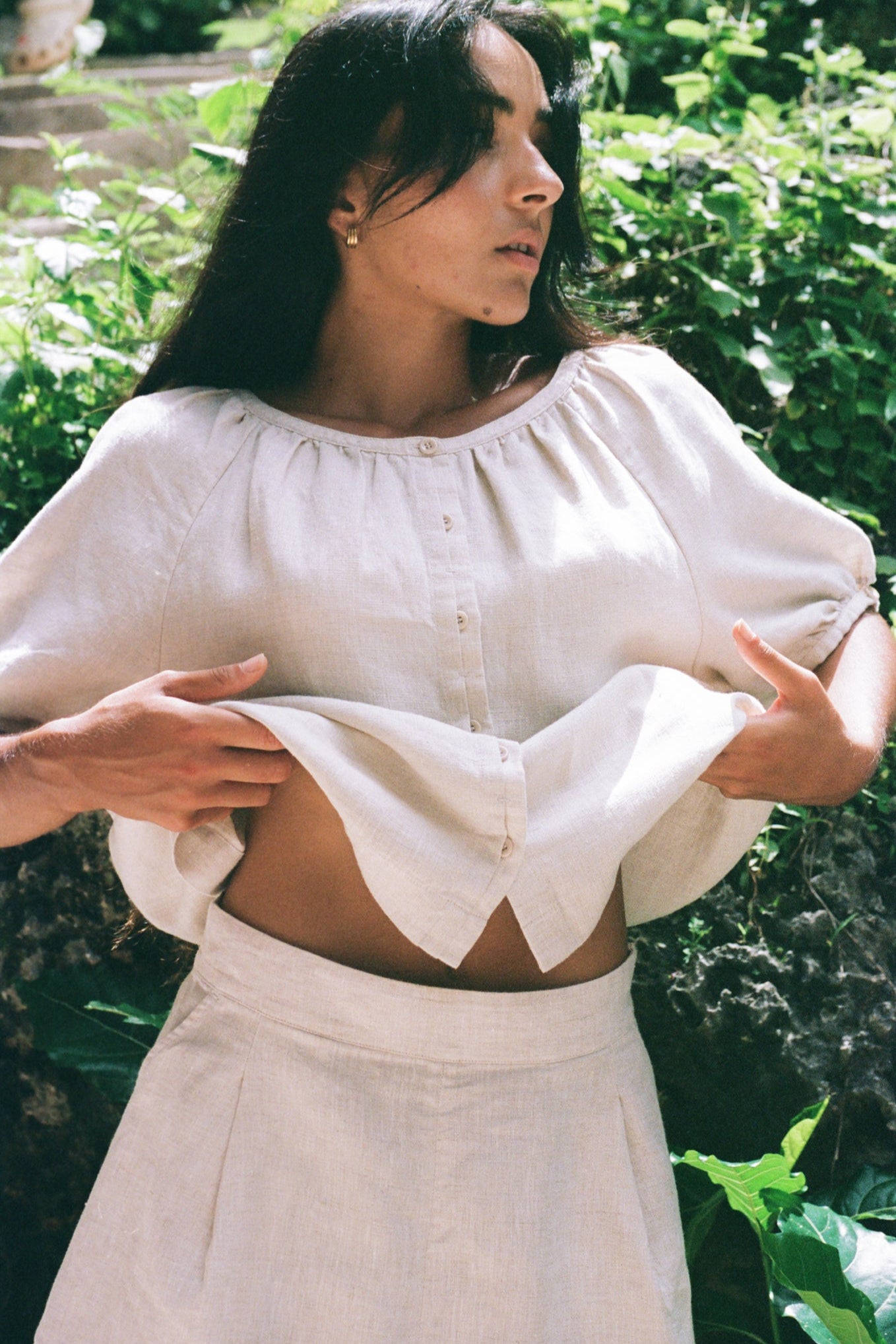 LILLY PILLY woman wearing a oatmeal Pia linen short top with bell sleeves in a garden setting