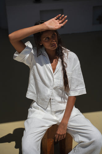 Quinn Linen Shirt in Ivory - front view with hand shading face paired with matching Rika ivory pants in a studio setting - Lilly Pilly Collection