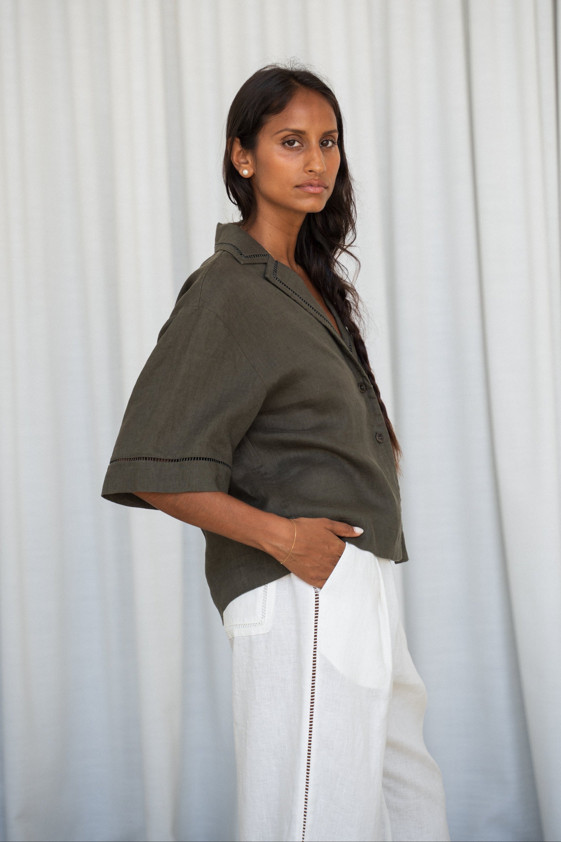 LILLY PILLY woman wearing a Pixie linen shirt in khaki against a white curtain background