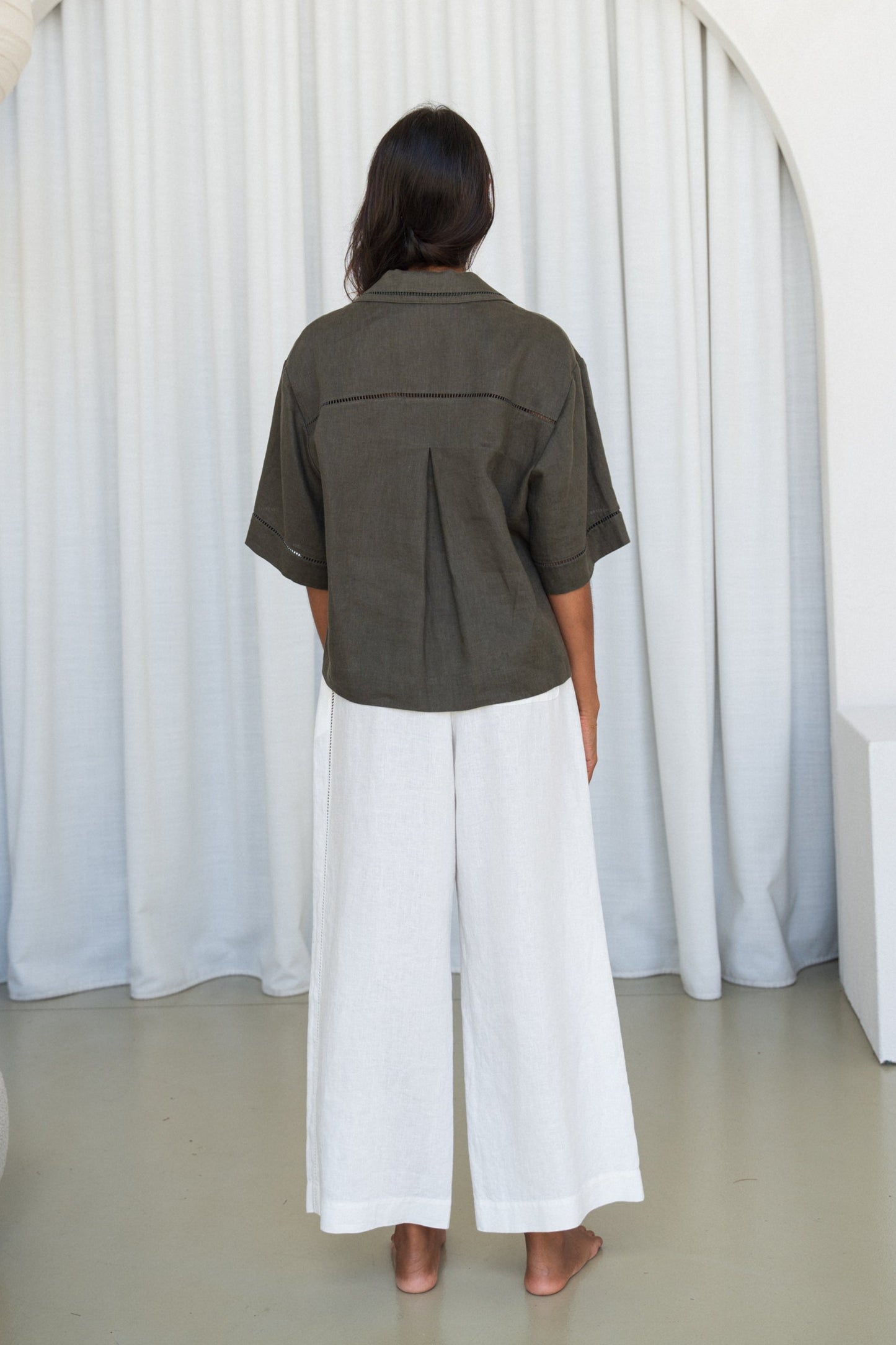 LILLY PILLY woman wearing a Pixie linen shirt in khaki with ivory linen pants,  back view