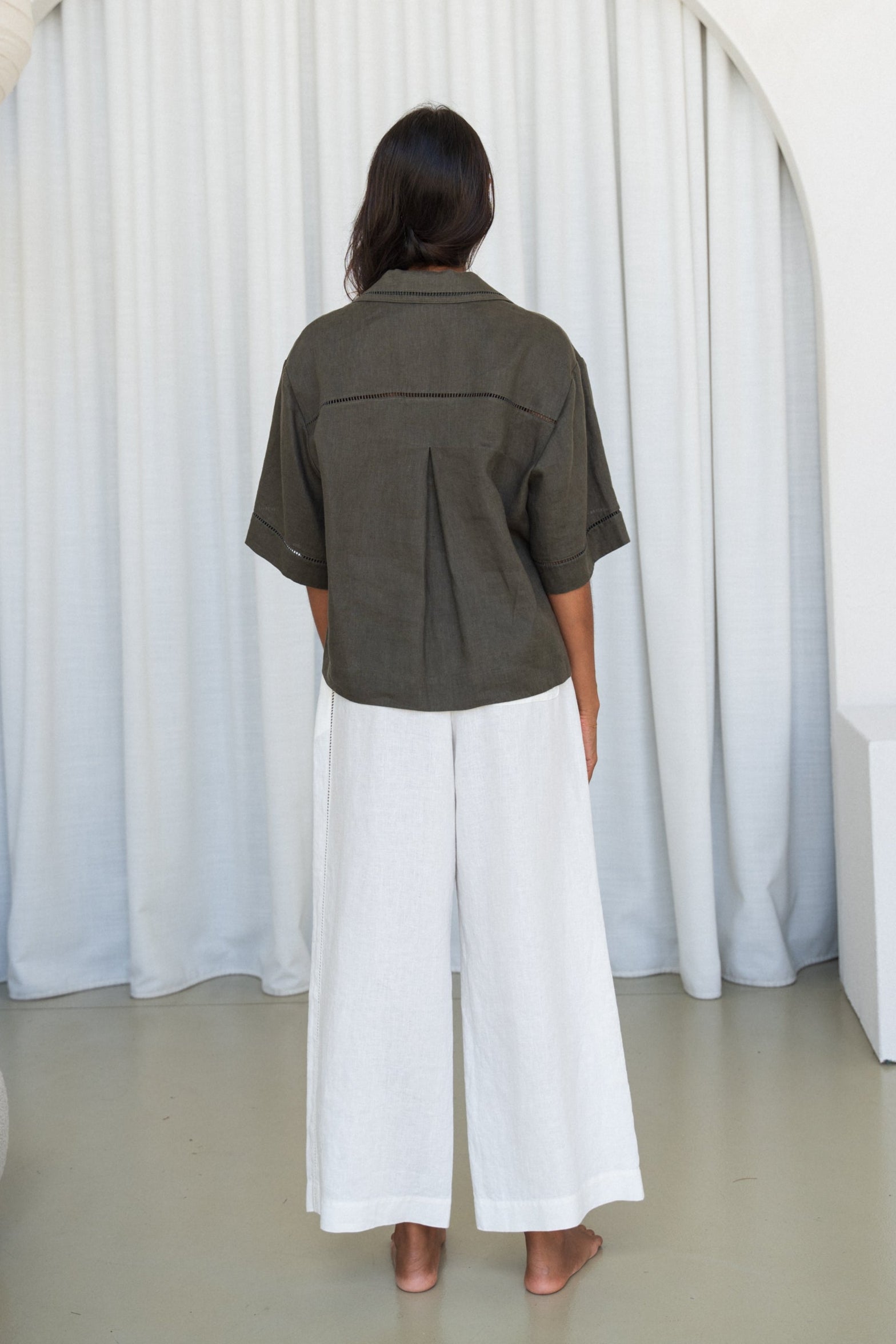 LILLY PILLY woman wearing a Pixie linen shirt in khaki with ivory linen pants,  back view