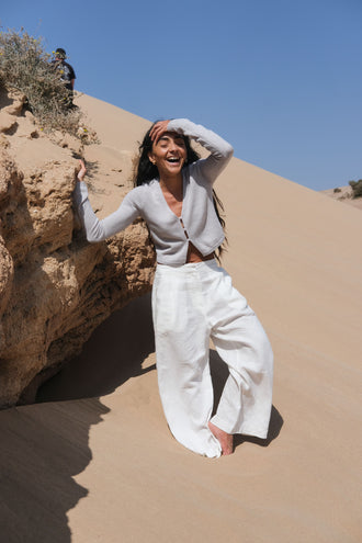 Rika Linen Pants in Ivory - full front view paired with Taylor Fog Grey knit while touching a rock - Lilly Pilly Collection