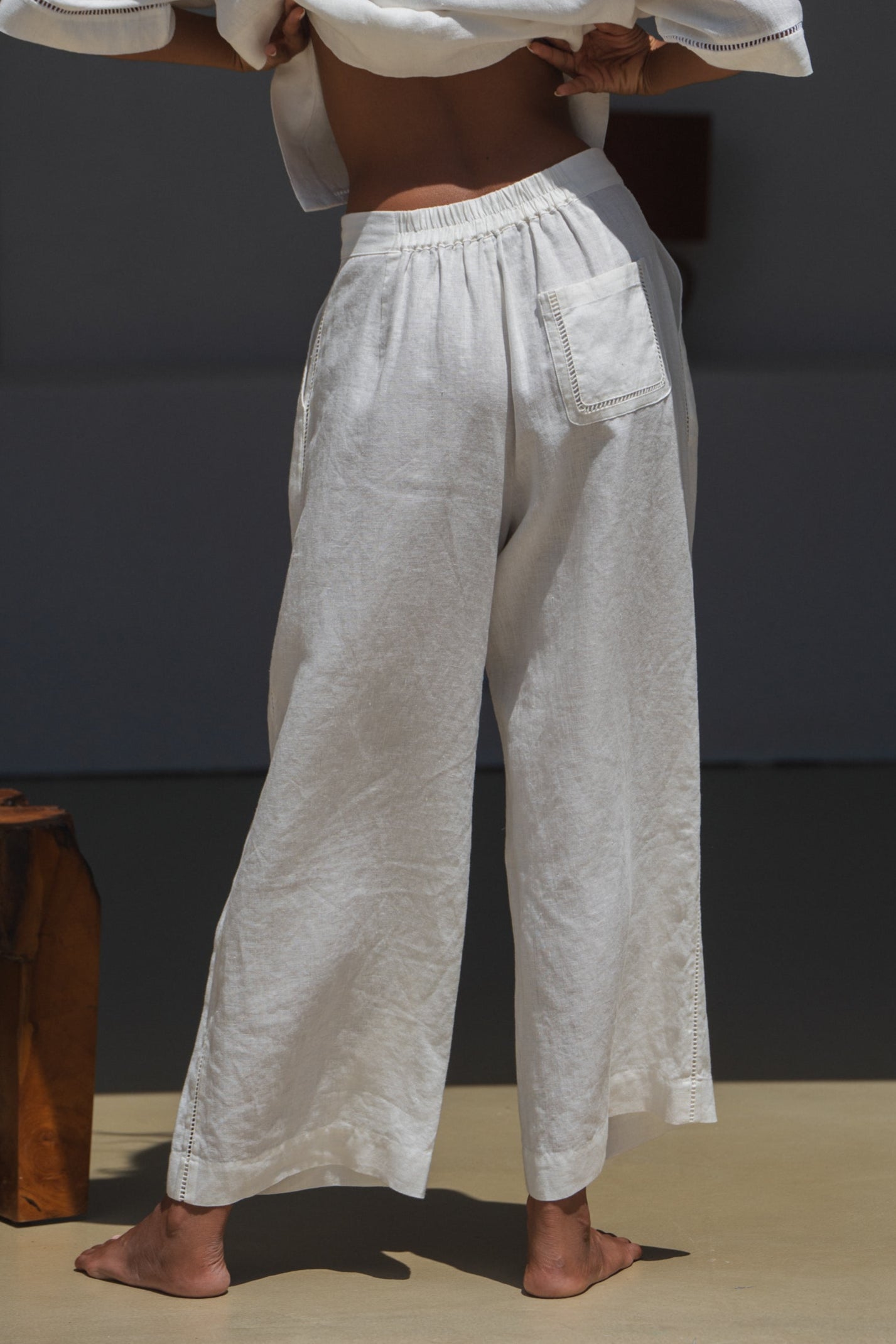 Woman in a ivory Rika linen pants, back view