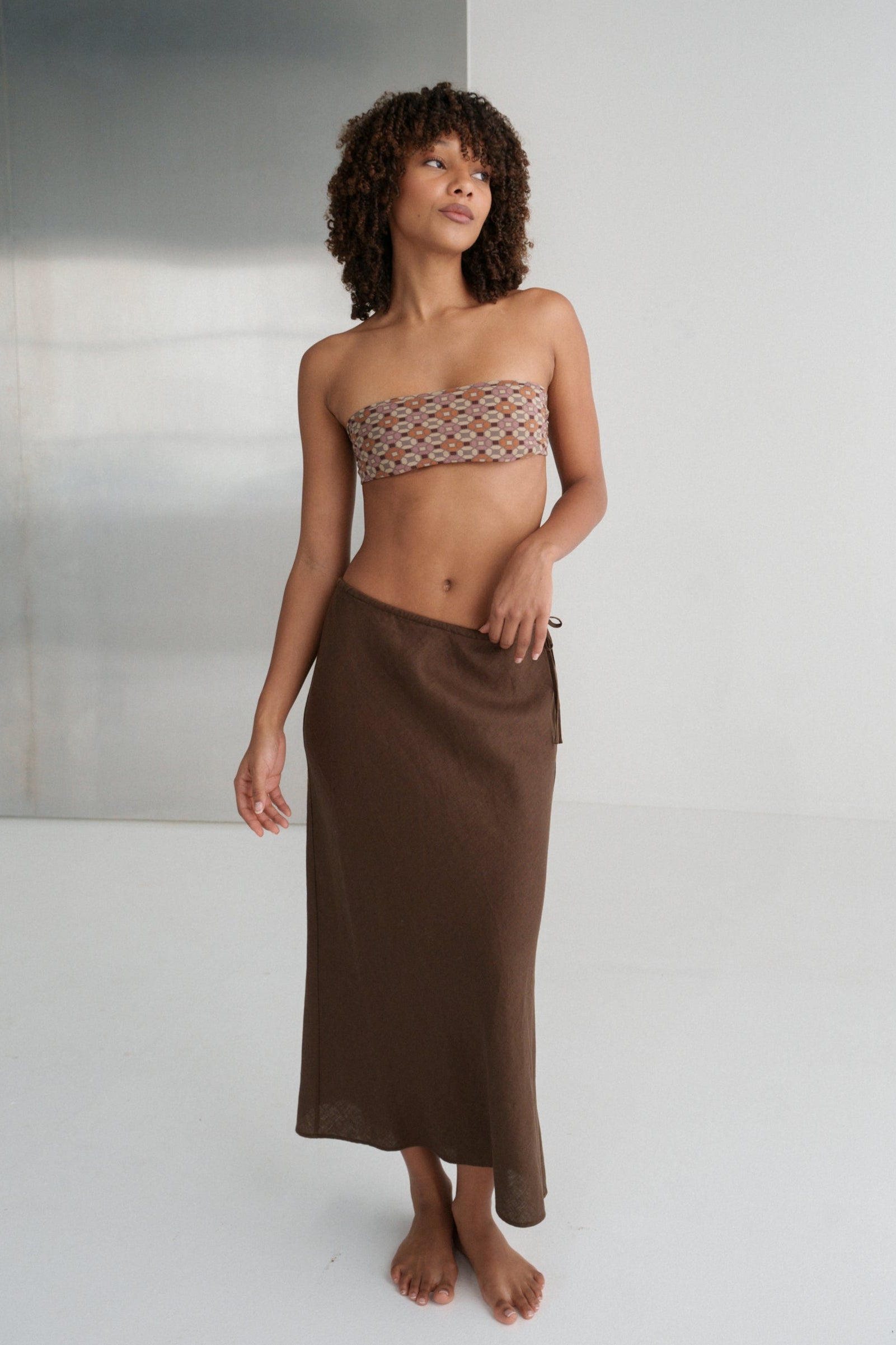 LILLY PILLY woman wearing Riley bias cut linen skirt  in chocolate brown against a white background