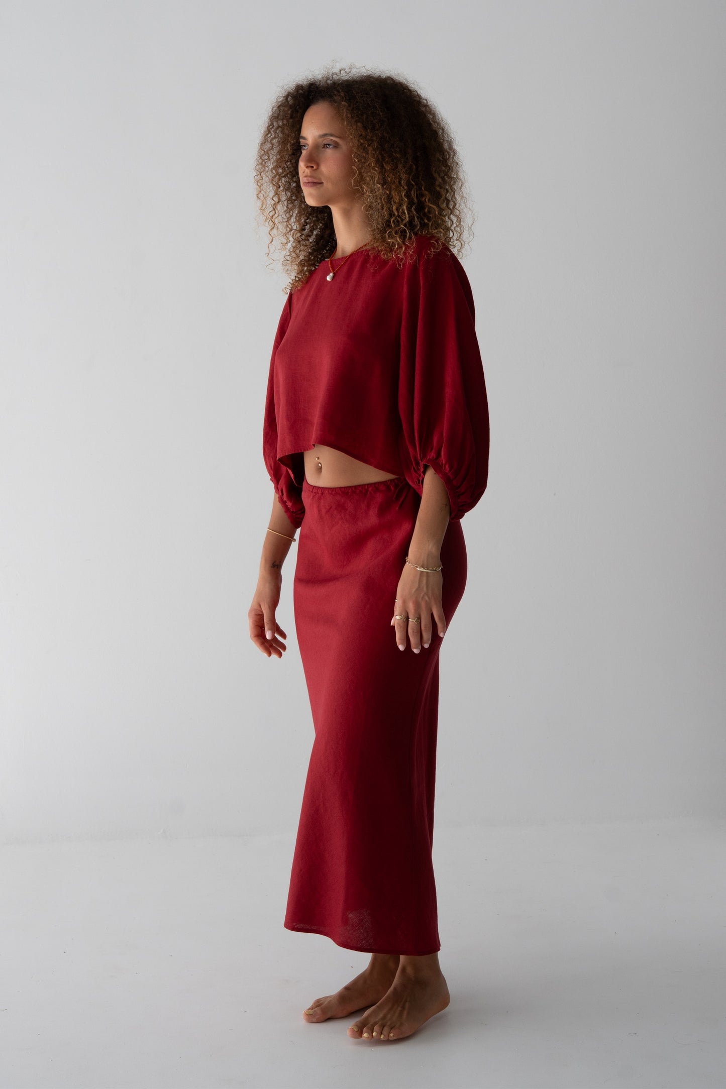 Riley Bias Linen Midi Skirt in Cherry Red - side view, woman wearing Cherry Red linen skirt with matching balloon-sleeve linen crop top - Lilly Pilly Collection
