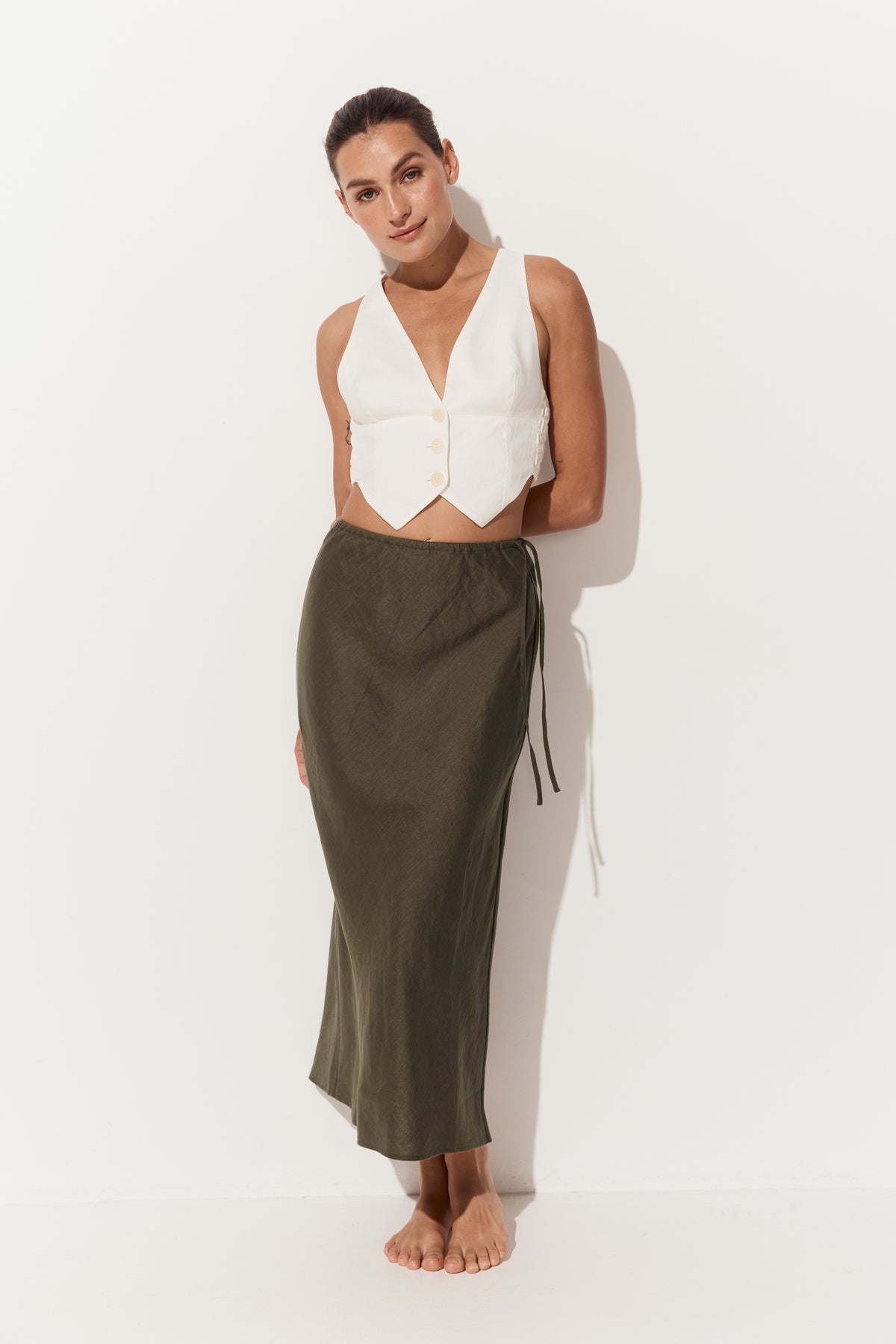 Riley Bias Linen Midi Skirt in Khaki - full front view of woman wearing skirt paired with Ari linen ivory vest - Lilly Pilly Collection