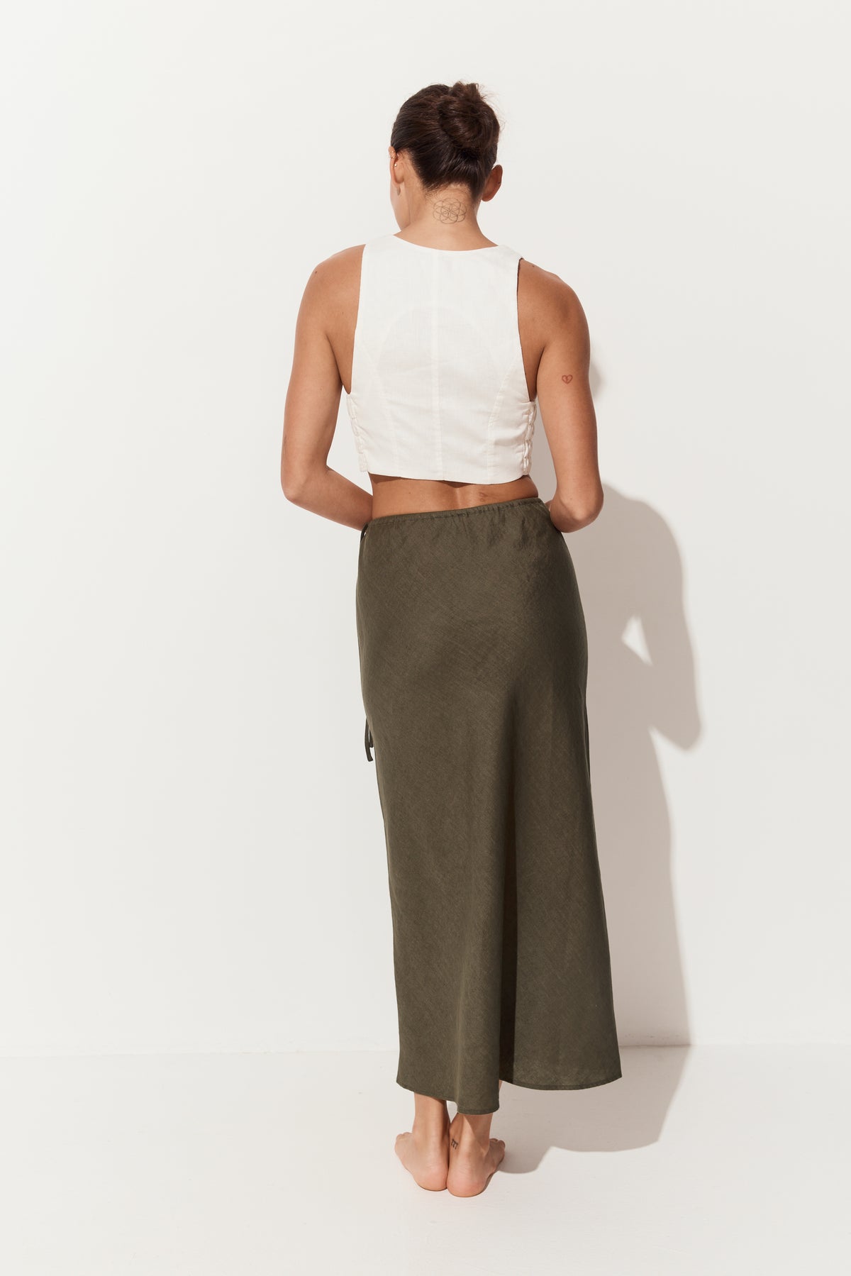 Riley Bias Linen Midi Skirt in Khaki - back view of woman wearing skirt paired with Ari linen ivory vest - Lilly Pilly Collection