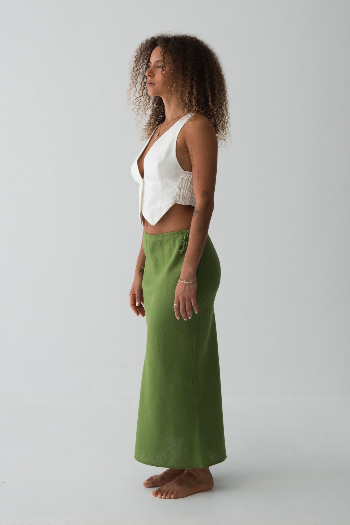 Riley Bias Linen Midi Skirt in Lime Green - side view, bias-cut midi length, side tie detail, worn with ivory waistcoat crop top, gold bracelet - Lilly Pilly Collection