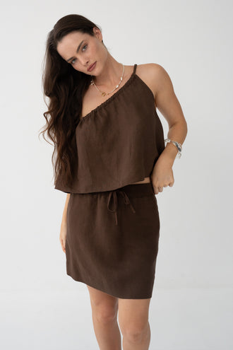 Romy Linen Top in Chocolate - three-quarter view, one-shoulder gathered neckline, styled with Anelle Linen Mini Skirt in Chocolate - Lilly Pilly Collection
