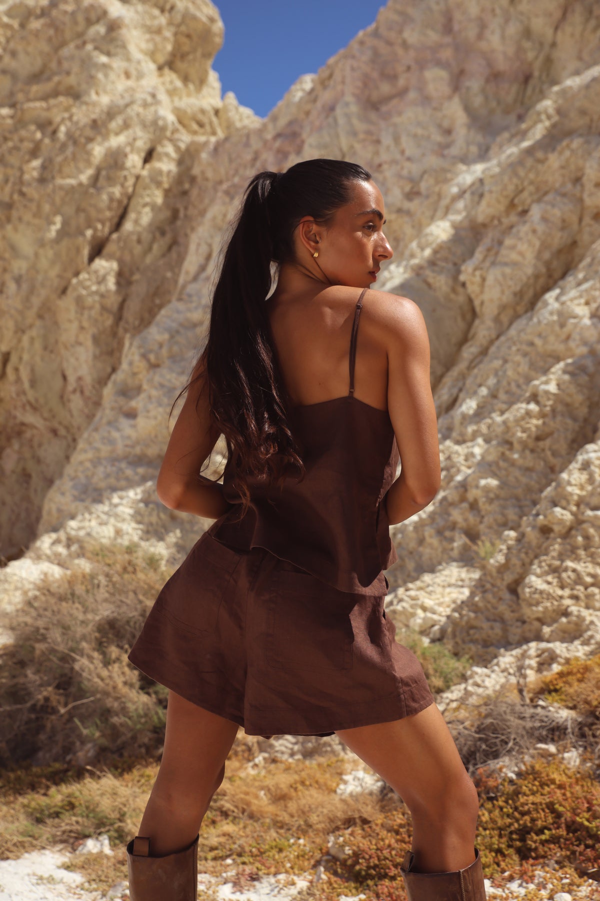 Rosa Linen Cami in Chocolate - back view, spaghetti straps and open back, styled with Gaia Linen Shorts in Chocolate and knee-high boots, rocky cliff backdrop - Lilly Pilly Collection