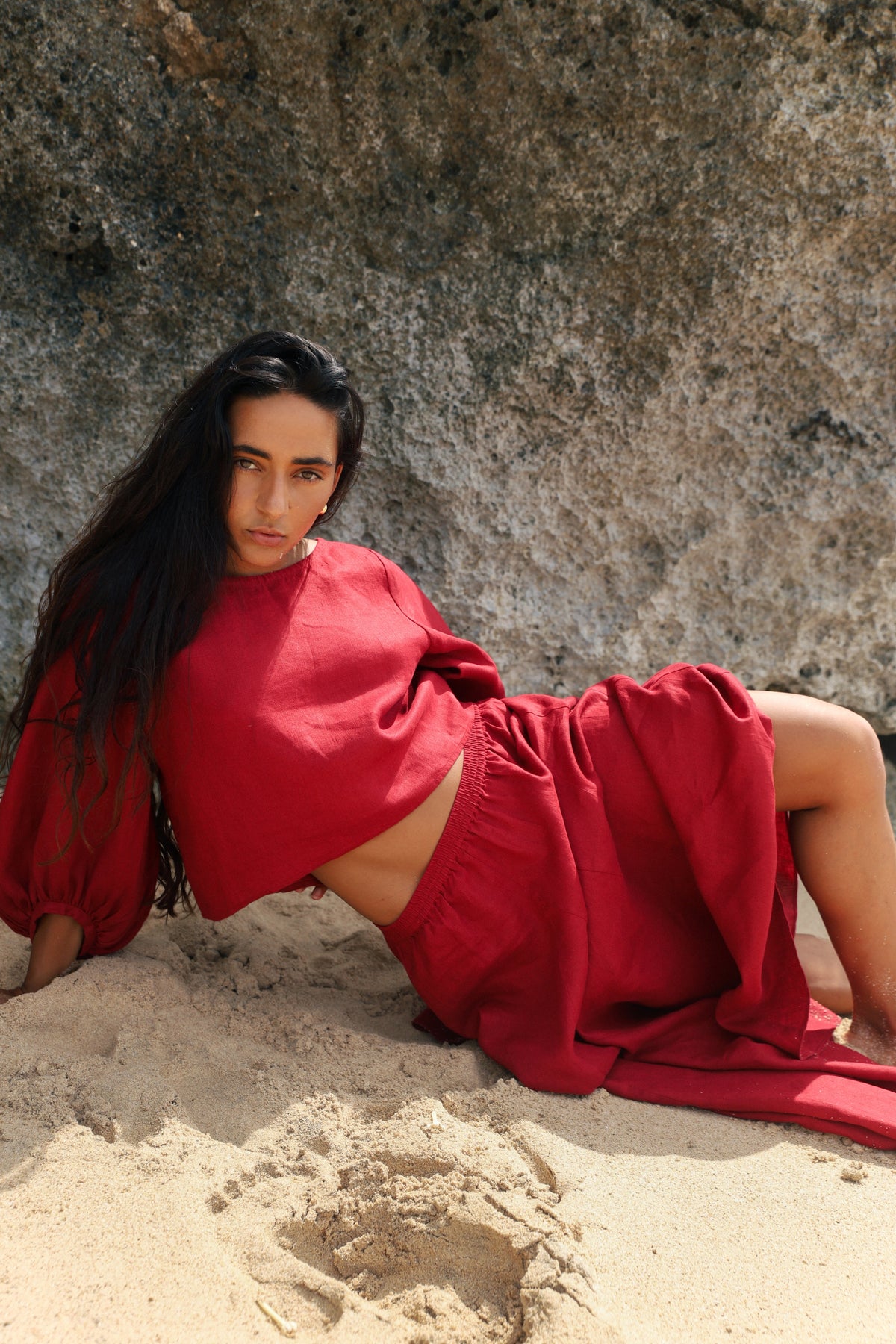 Stella Linen Maxi Skirt in Cherry Red - full length, woman wearing matching Cherry Red linen puff-sleeve crop top, coastal rock backdrop - Lilly Pilly Collection