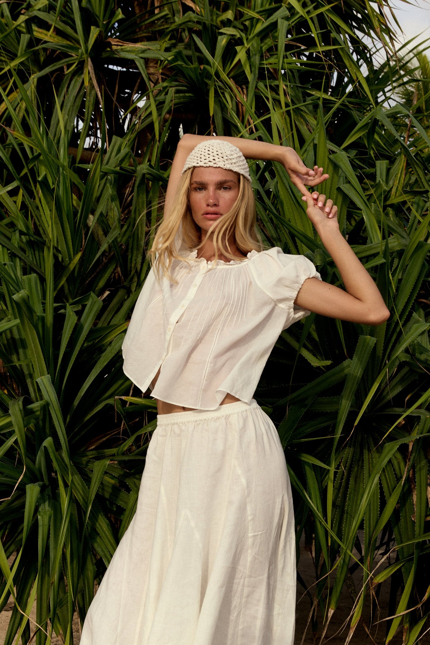 Stella Linen Maxi Skirt in Ivory - full length, woman wearing Ivory linen skirt with ivory pintuck crop top and woven headband, tropical foliage backdrop - Lilly Pilly Collection