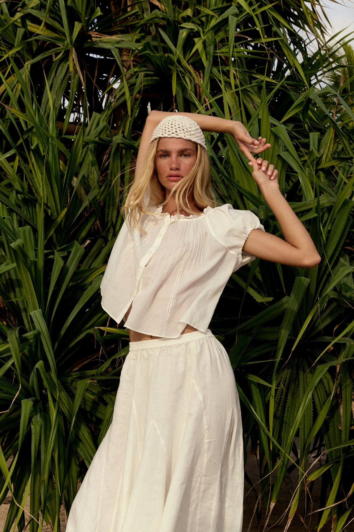 Stella Linen Maxi Skirt in Ivory - full length, woman wearing Ivory linen skirt with ivory pintuck crop top and woven headband, tropical foliage backdrop - Lilly Pilly Collection