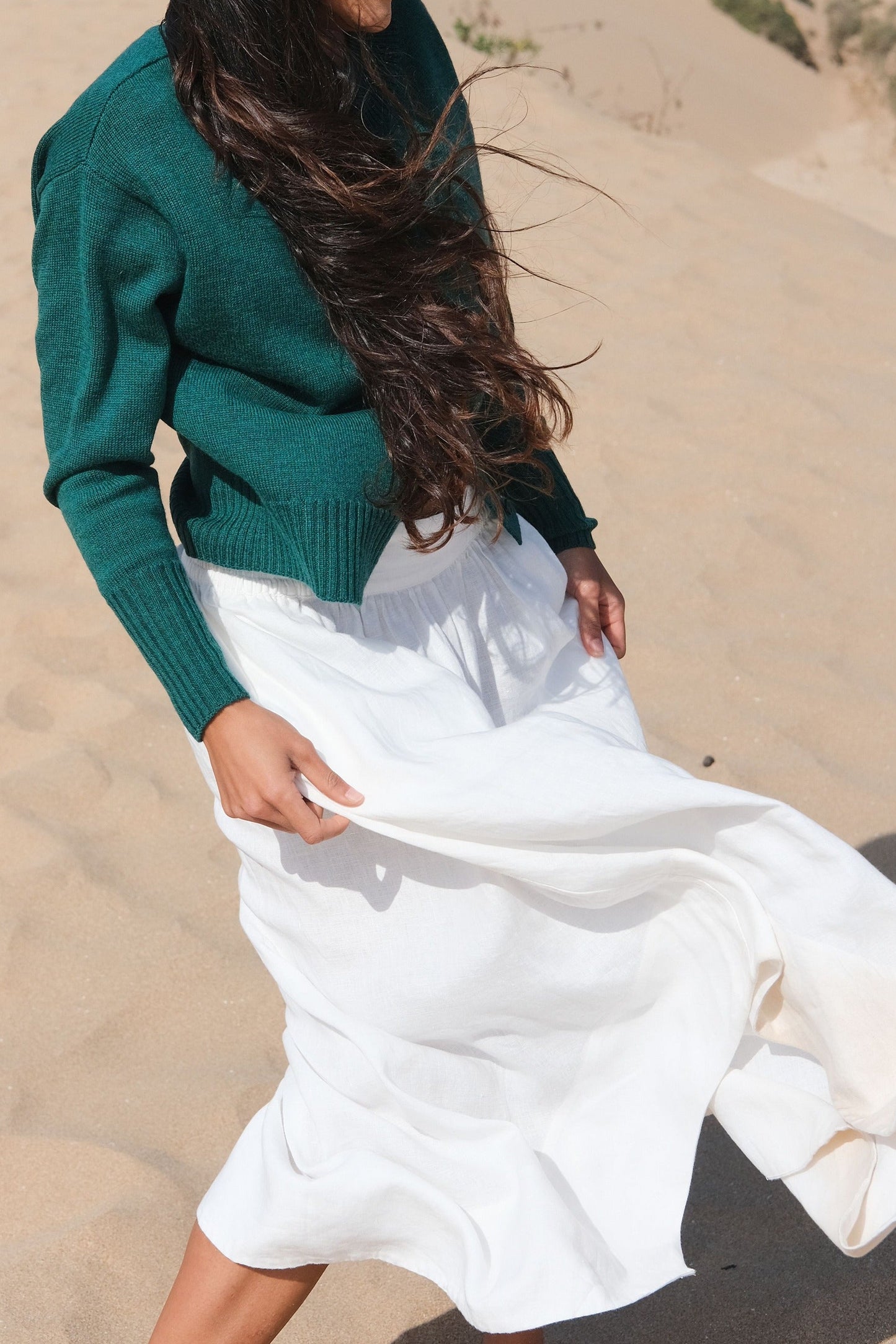 LILLY PILLY woman wearing pine green coloured Taylor merino knit cardigan standing on sand dunes with a desert landscape in the background