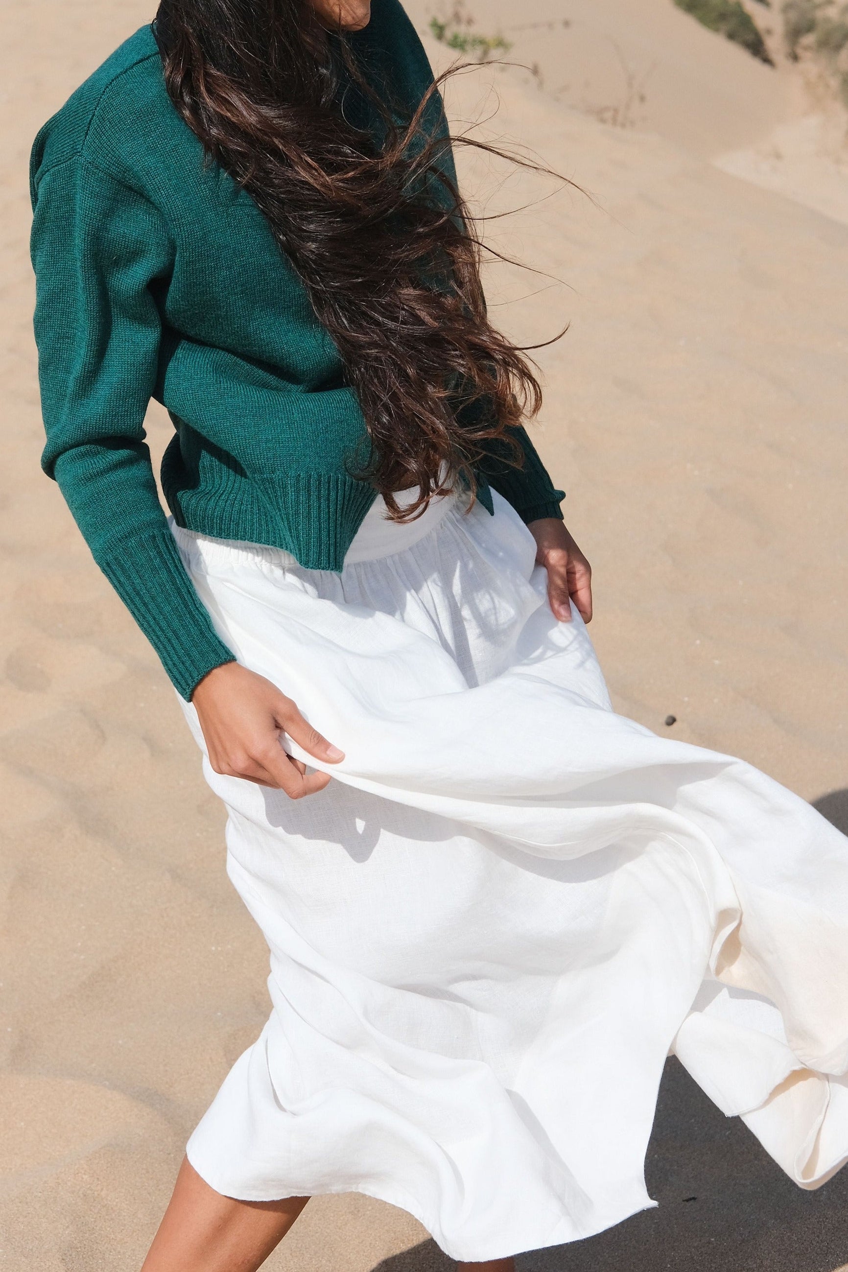 LILLY PILLY woman wearing pine green coloured Taylor merino knit cardigan standing on sand dunes with a desert landscape in the background
