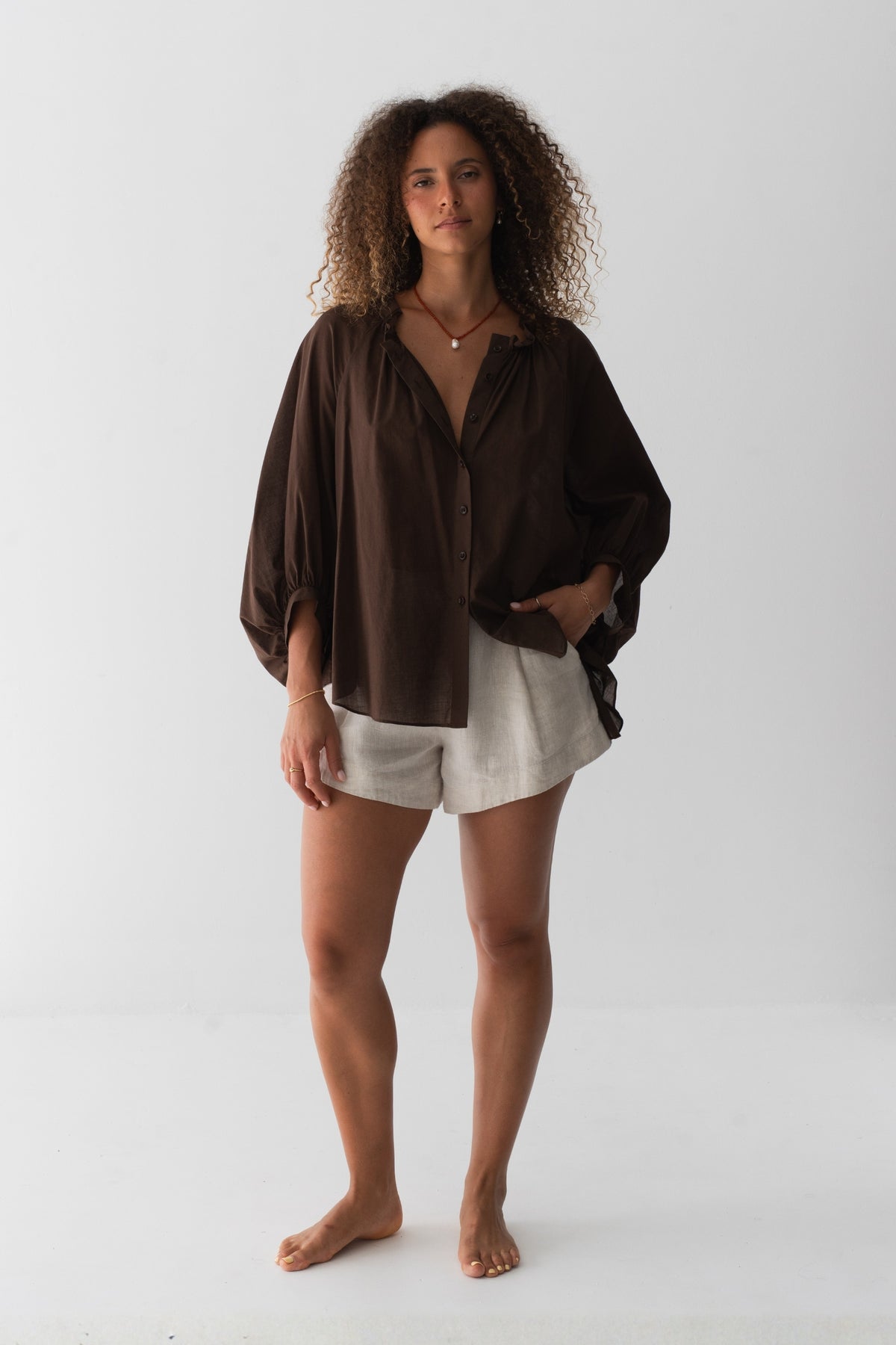 Thalia Cotton Voile Shirt in Chocolate - front view, gathered neckline and button-front, balloon sleeves, worn over Gaia Linen Shorts in Oatmeal - Lilly Pilly Collection