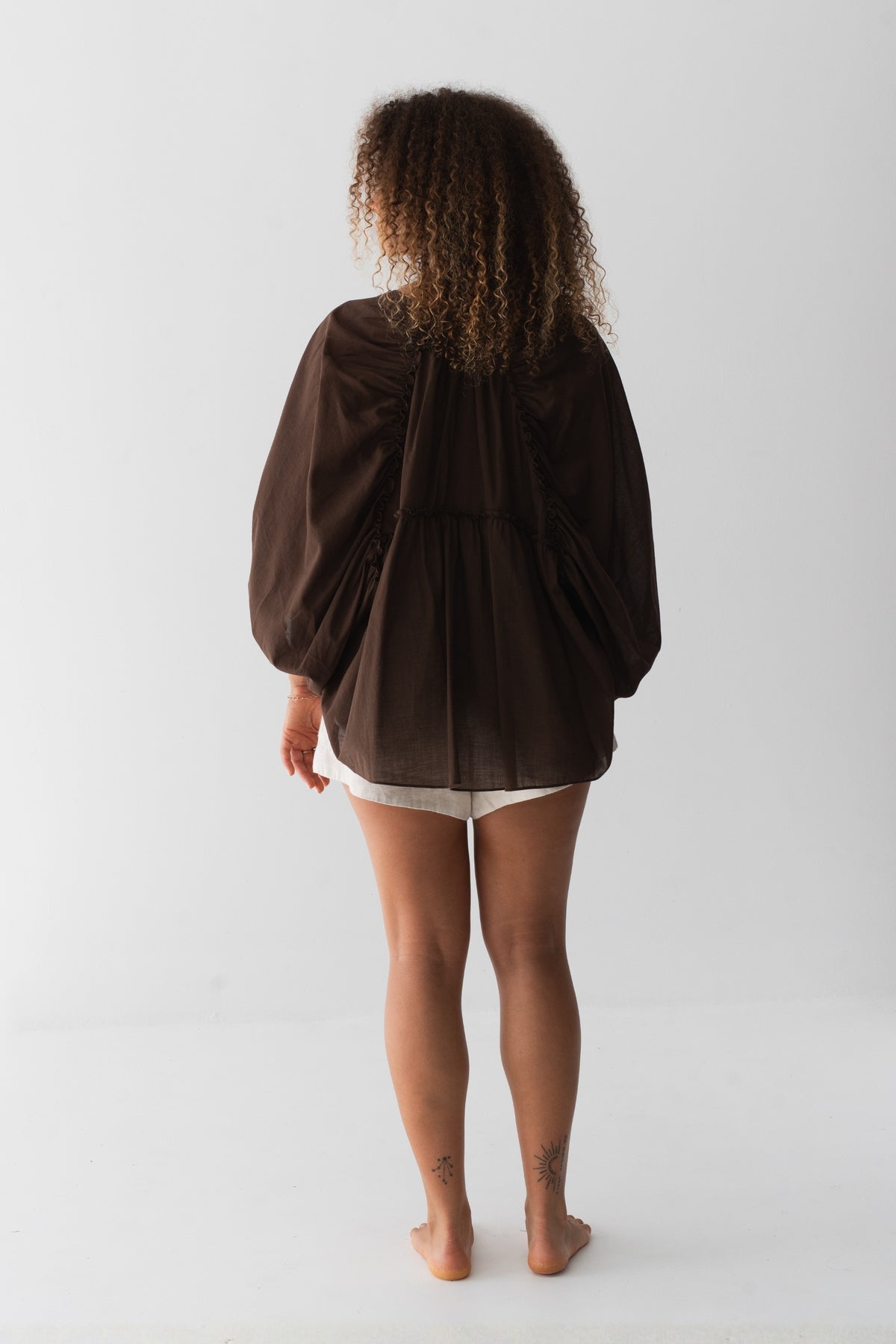 Thalia Cotton Voile Shirt in Chocolate - back view, gathered back yoke and balloon sleeves, worn over Gaia Linen Shorts in Oatmeal - Lilly Pilly Collection